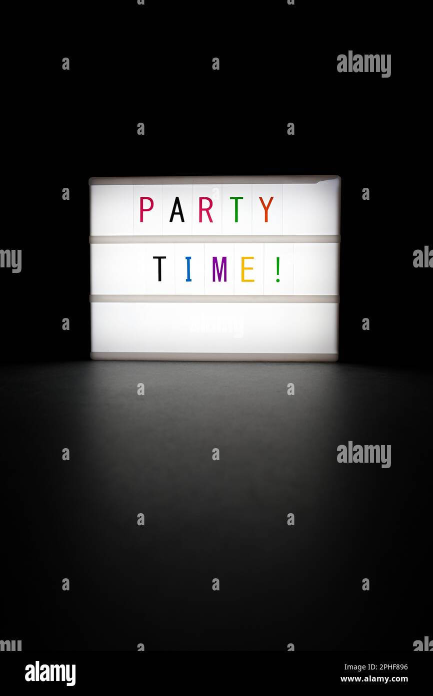 Le néon lumineux ''Party Time' est dans l'obscurité sur fond noir Banque D'Images