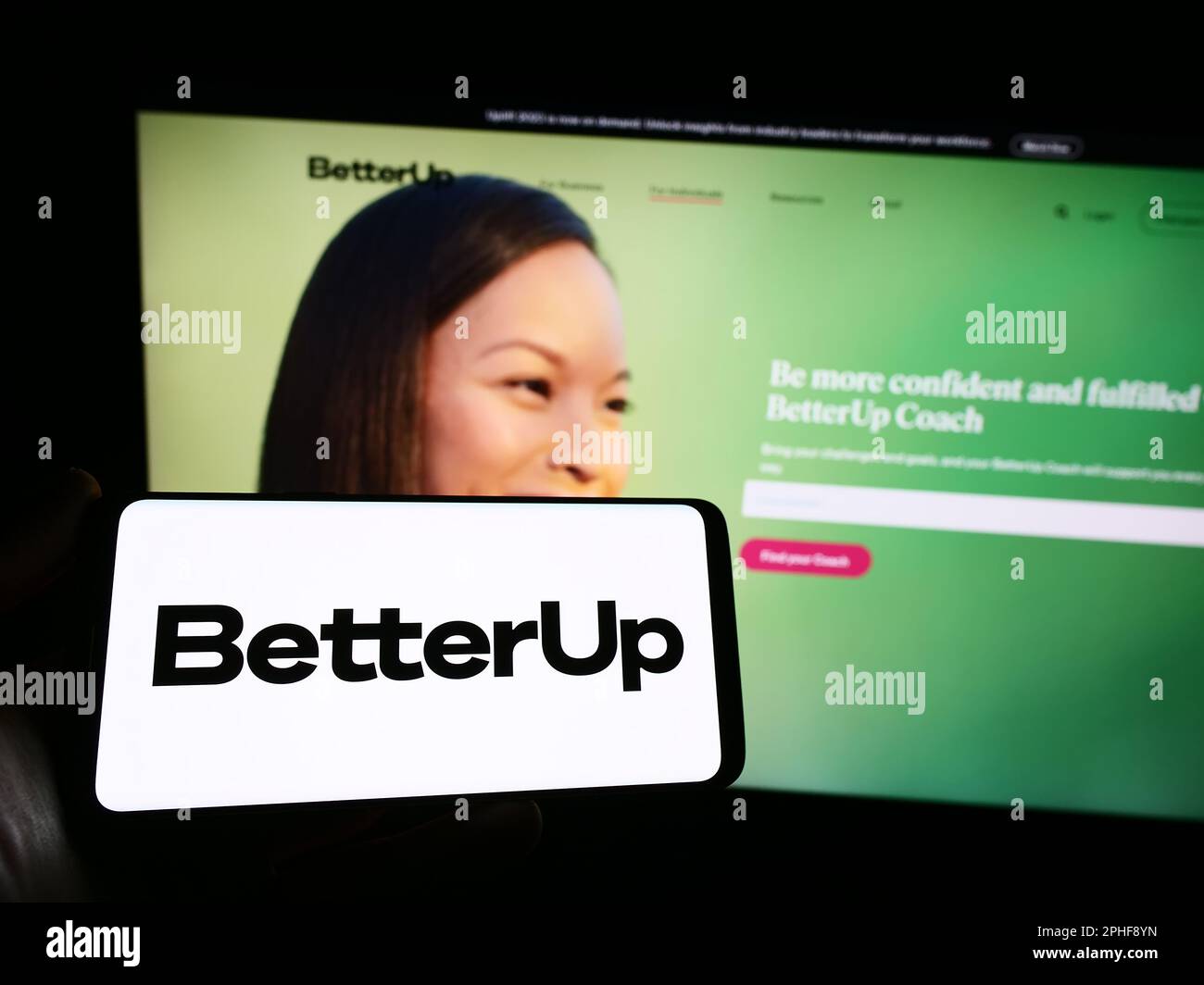 Personne tenant un smartphone avec le logo de la société de coaching américaine BetterUp à l'écran devant le site Web. Mise au point sur l'affichage du téléphone. Banque D'Images