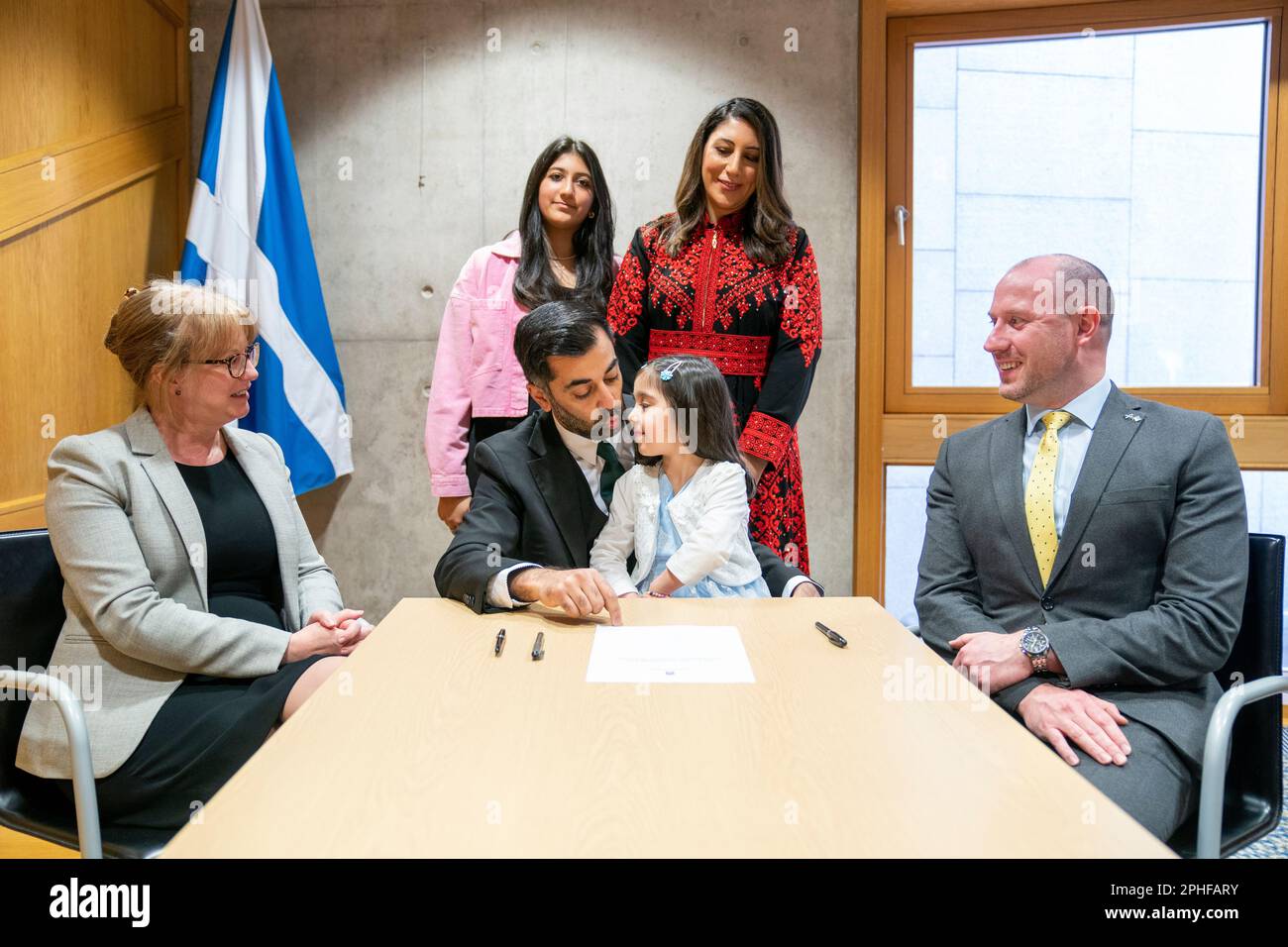 Humza Yousaf, le nouveau chef du Parti national écossais, signe le formulaire de nomination pour devenir Premier ministre écossais, sous la surveillance de son épouse Nadia El-Nakla (en arrière à droite), de sa fille Amal, 3 ans, de sa belle-fille Maya (en arrière à gauche), de l'auteur de la proposition Shona Robison (à gauche) et du second Neil Gray, au Parlement écossais à Édimbourg. Le MSPS votera aujourd'hui la nomination de M. Yousaf au poste de sixième Premier ministre écossais. Date de la photo: Mardi 28 mars 2023. Banque D'Images