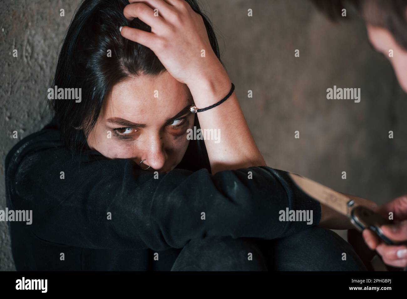 Femme kidnappée assise et menacée par un homme avec un couteau entre les mains dans un bâtiment