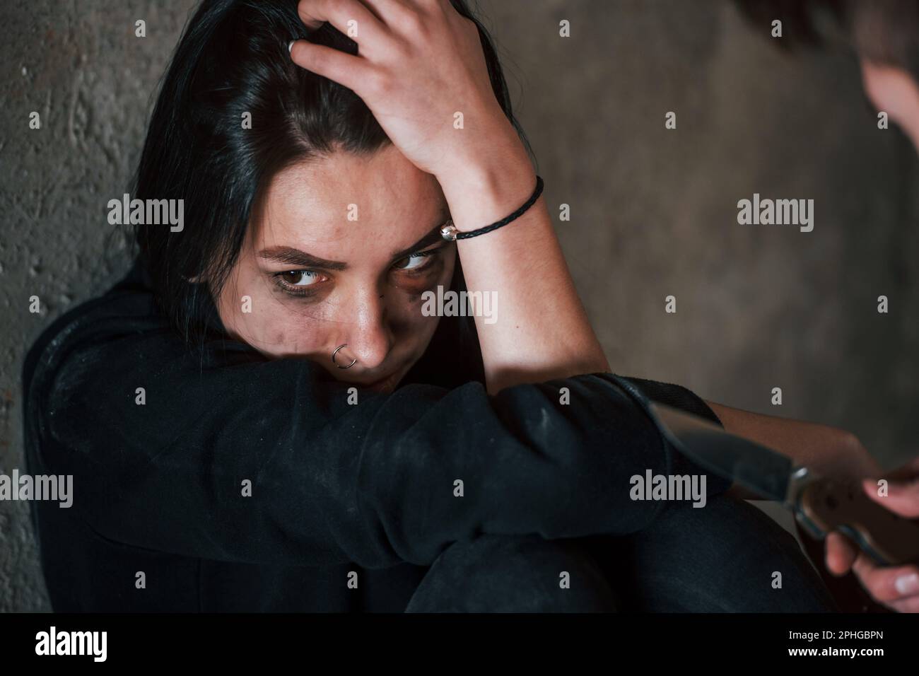 Femme kidnappée assise et menacée par un homme avec un couteau entre les mains dans un bâtiment