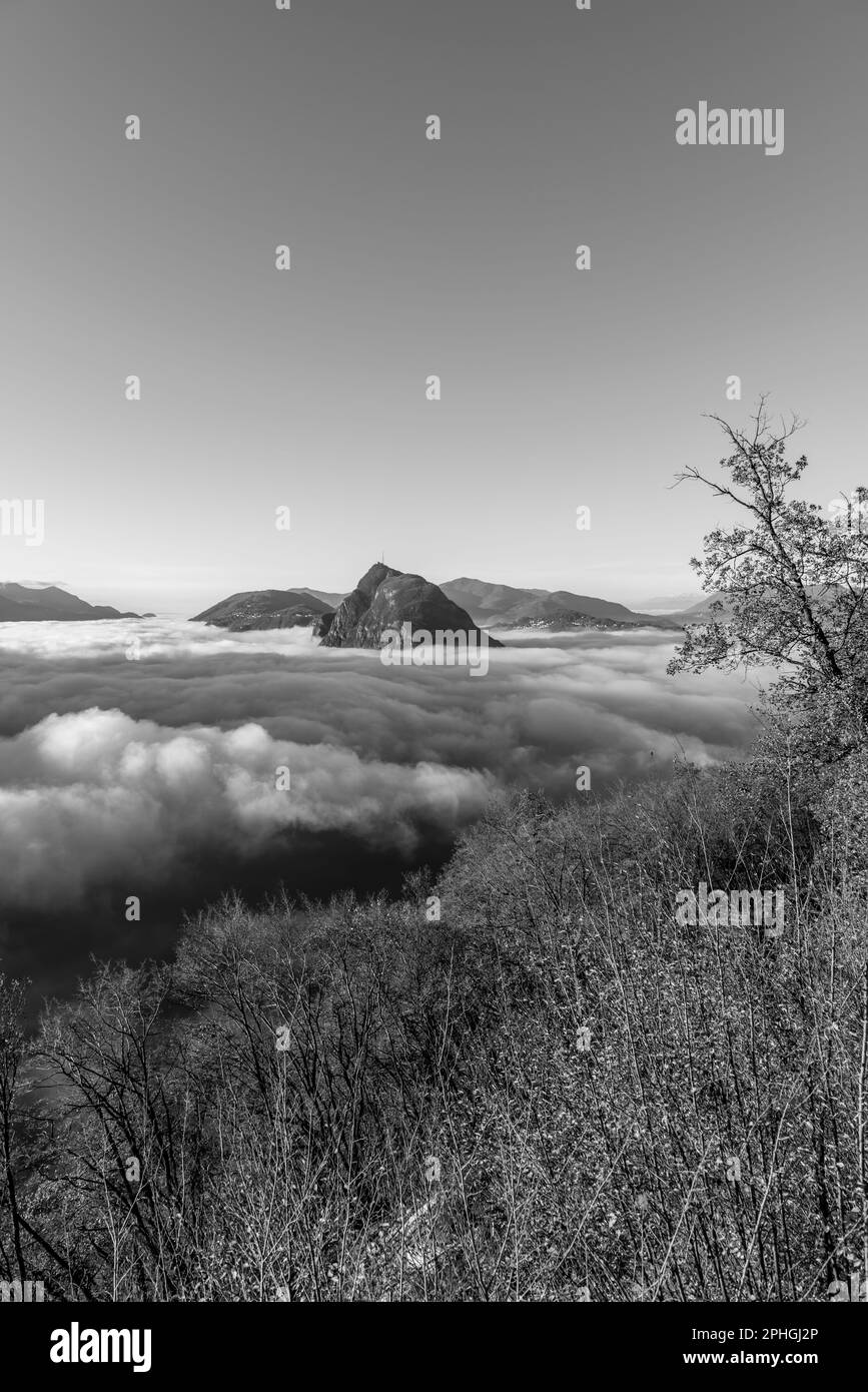 Mountain Peak San Salvatore au-dessus de Cloudscape avec un arbre d'automne et la lumière du soleil avec ciel clair à Lugano, Tessin en Suisse. Banque D'Images