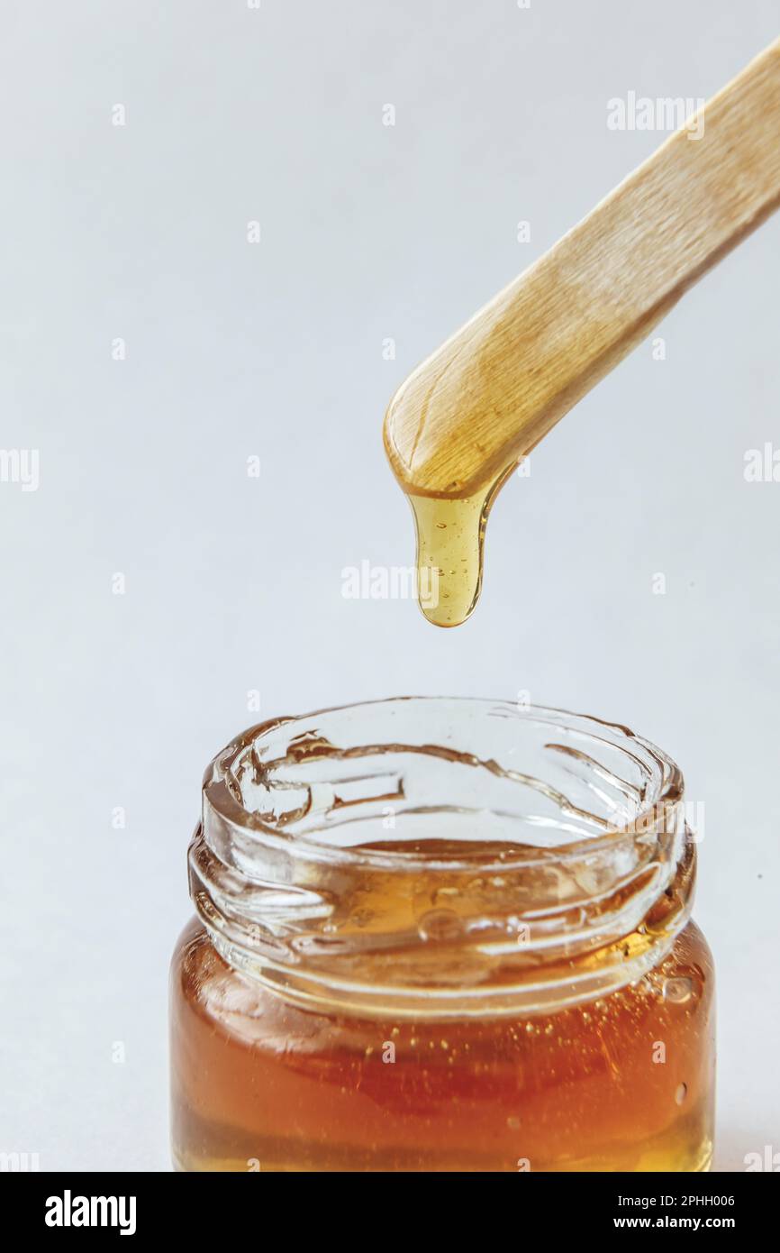 Pâte de sucre pour l'épilation à couper dans un pot en verre avec une  spatule en bois sur fond blanc. Miel naturel Photo Stock - Alamy