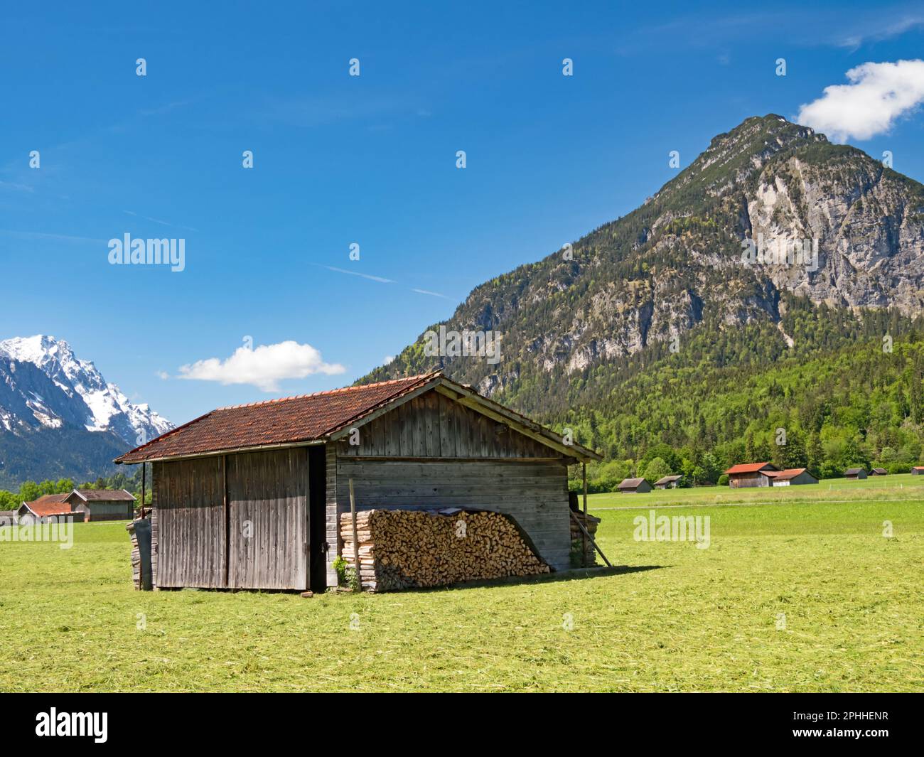 Grange en bois sur une prairie ensoleillée sur fond des Alpes d'Ammergau, Bavière, Allemagne Banque D'Images