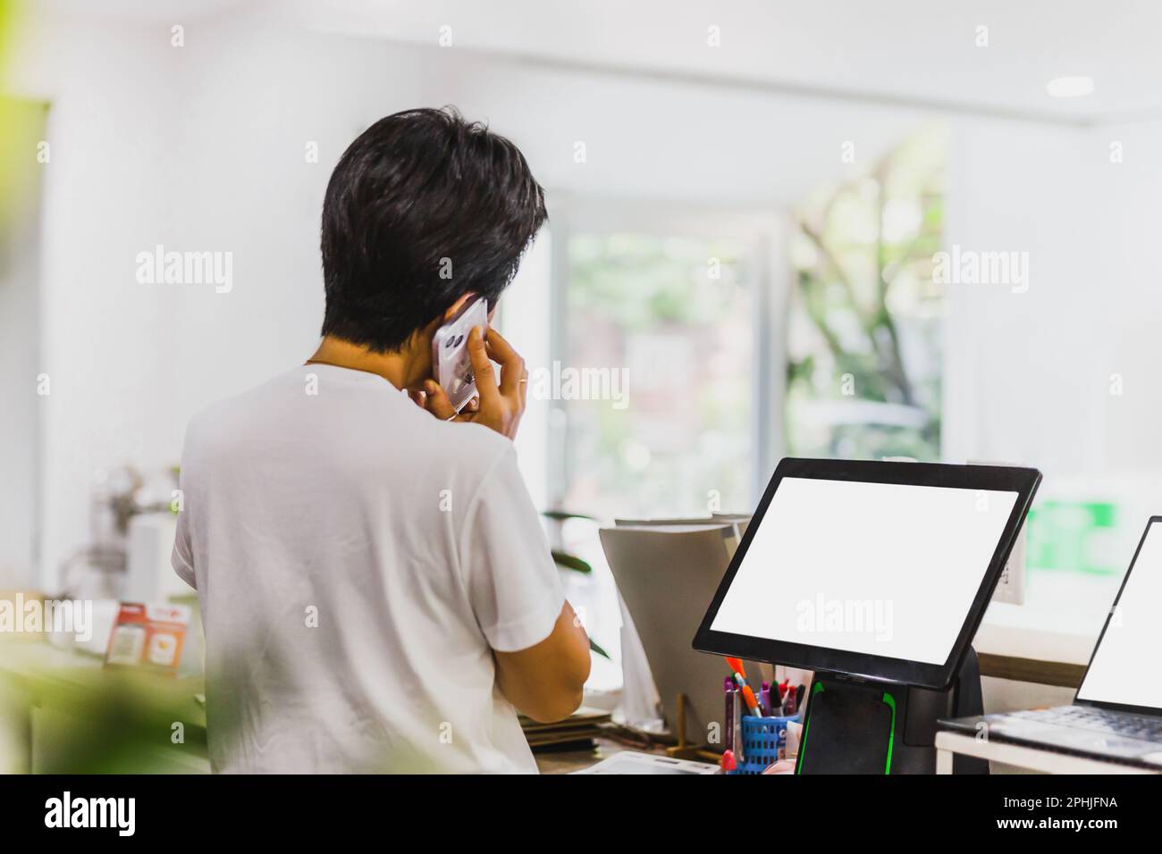 Femme au comptoir de caisse parlant sur téléphone portable. Banque D'Images