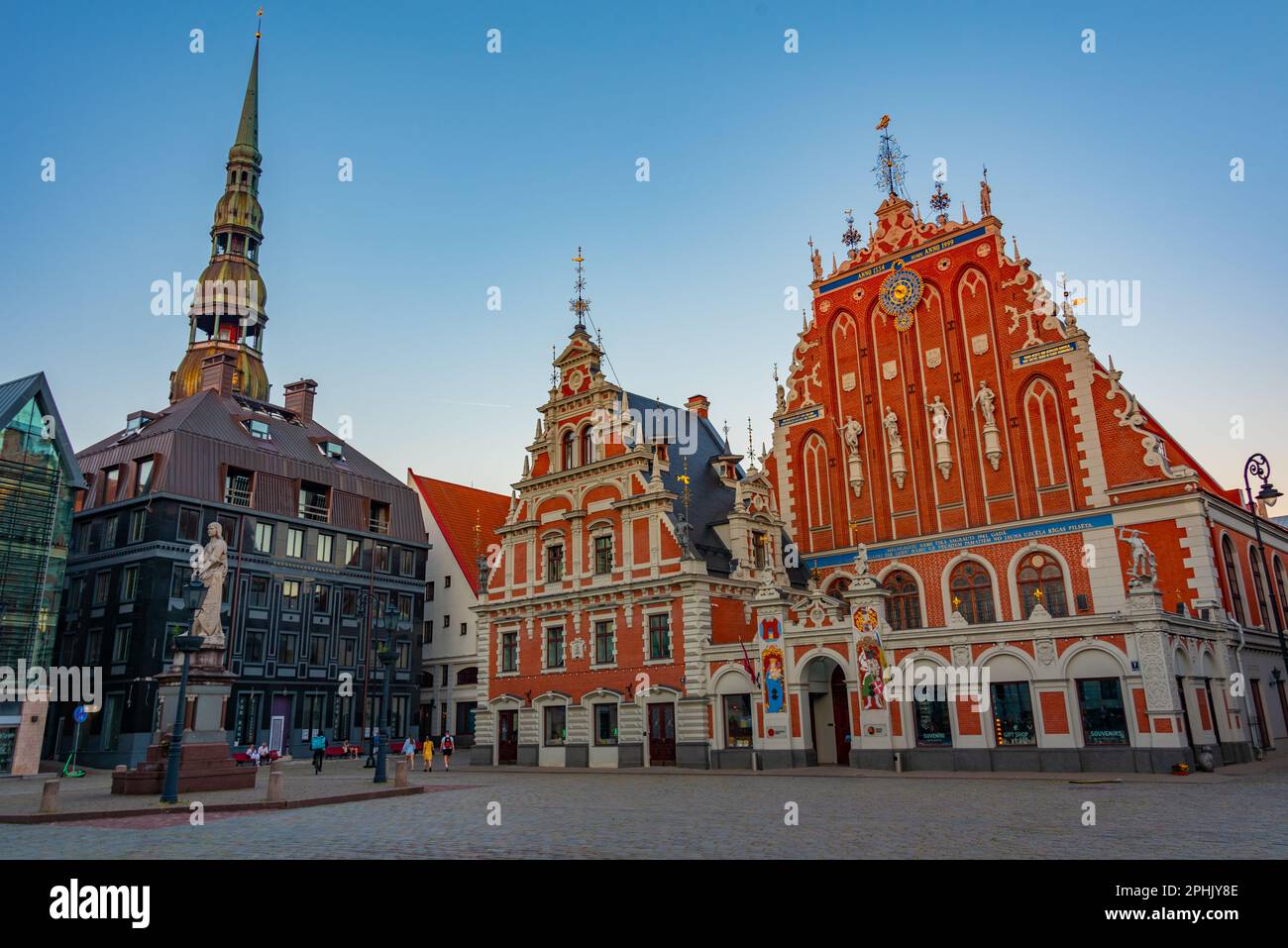 Coucher de soleil sur la place Ratslaukums avec église Saint-Pierre et Maison des Blackheads dans la vieille ville de Riga en Lettonie. Banque D'Images
