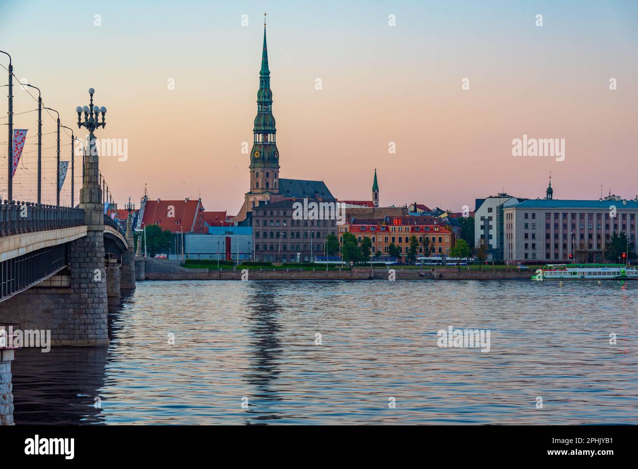Coucher de soleil dans la vieille ville de riga, y compris l'église saint peters vue sur la rivière daugava, Lettonie. Banque D'Images