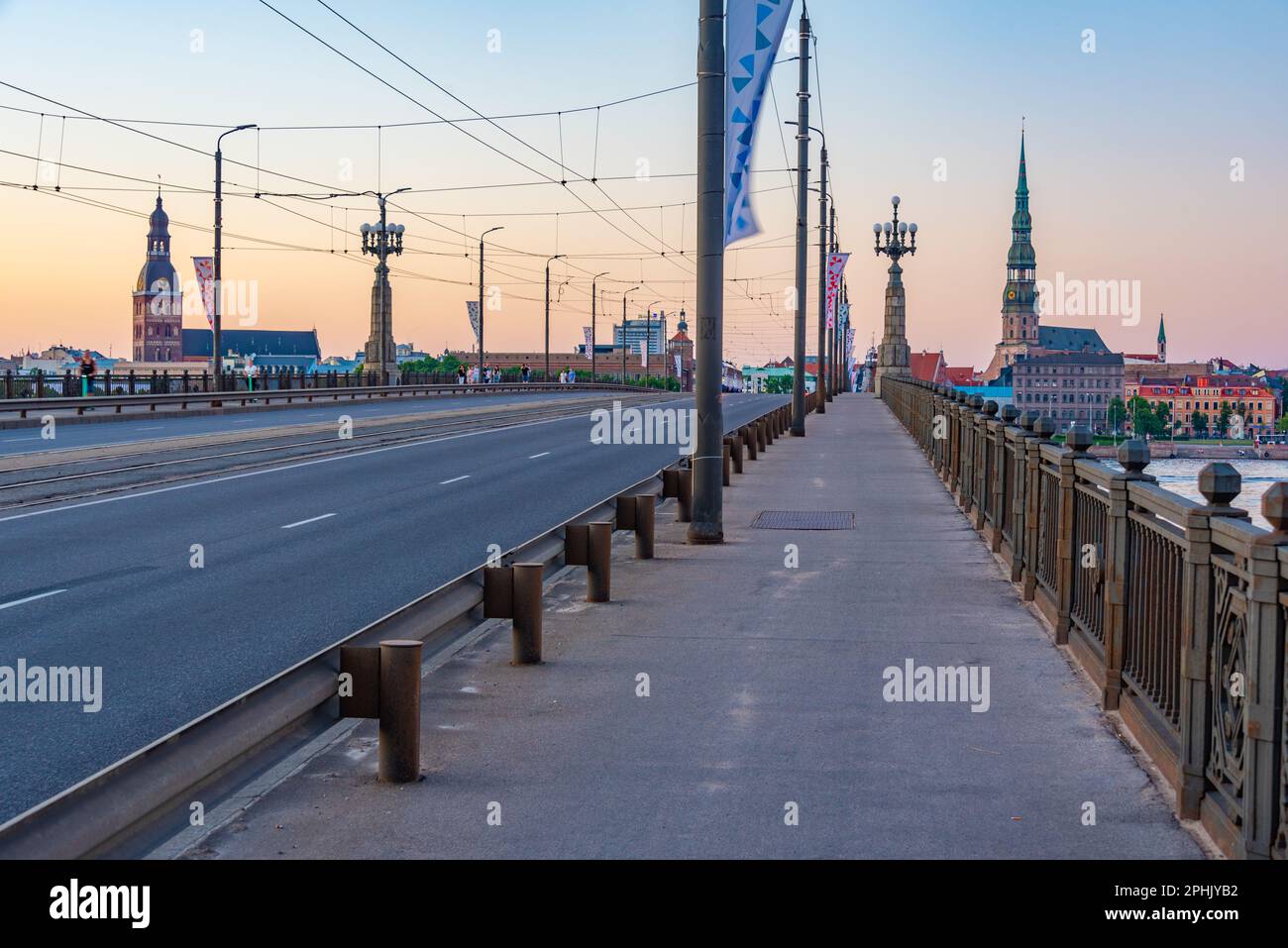 Coucher de soleil dans la vieille ville de riga, y compris l'église saint peters vue sur la rivière daugava, Lettonie. Banque D'Images