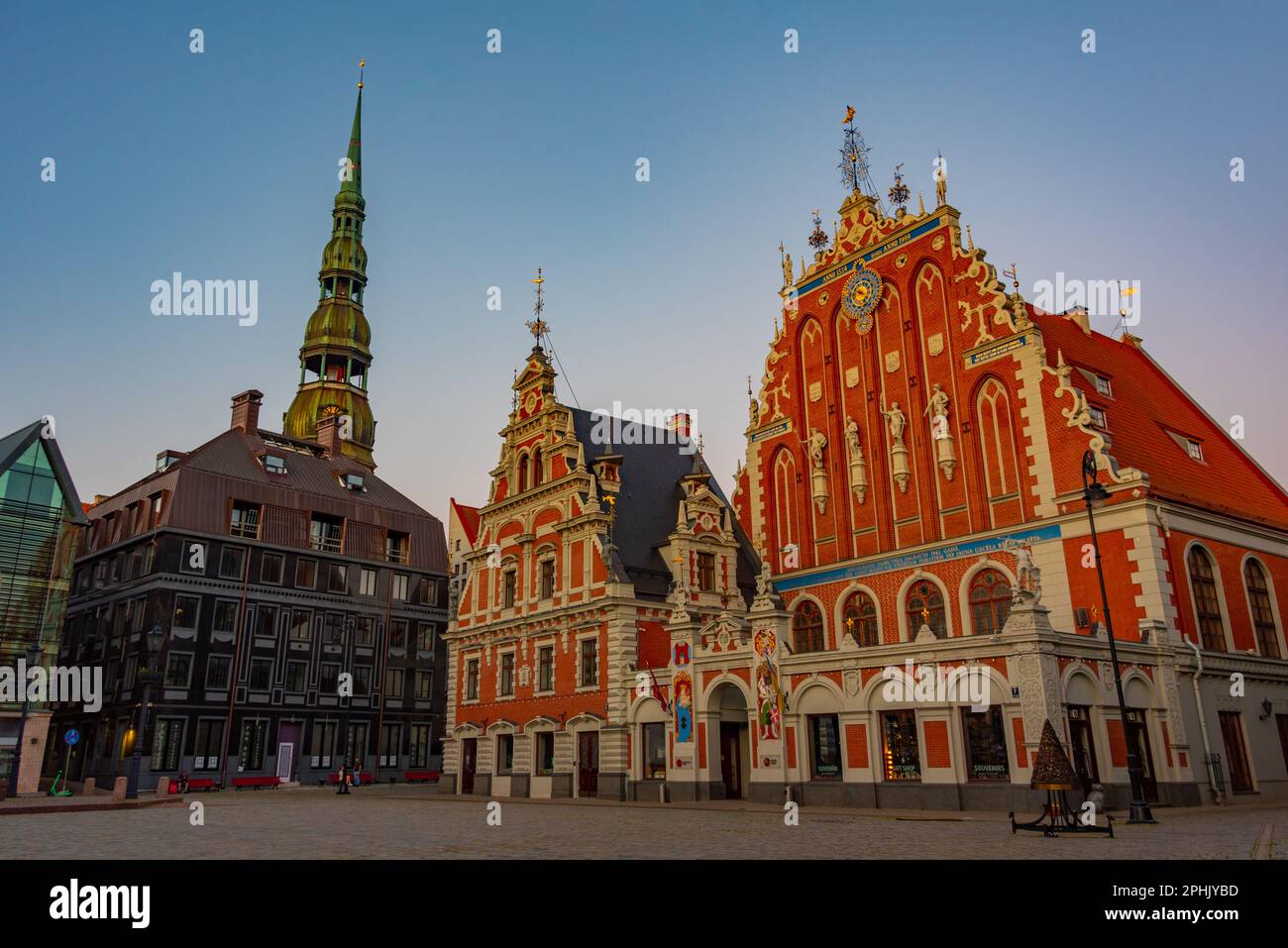 Coucher de soleil sur la place Ratslaukums avec église Saint-Pierre et Maison des Blackheads dans la vieille ville de Riga en Lettonie. Banque D'Images
