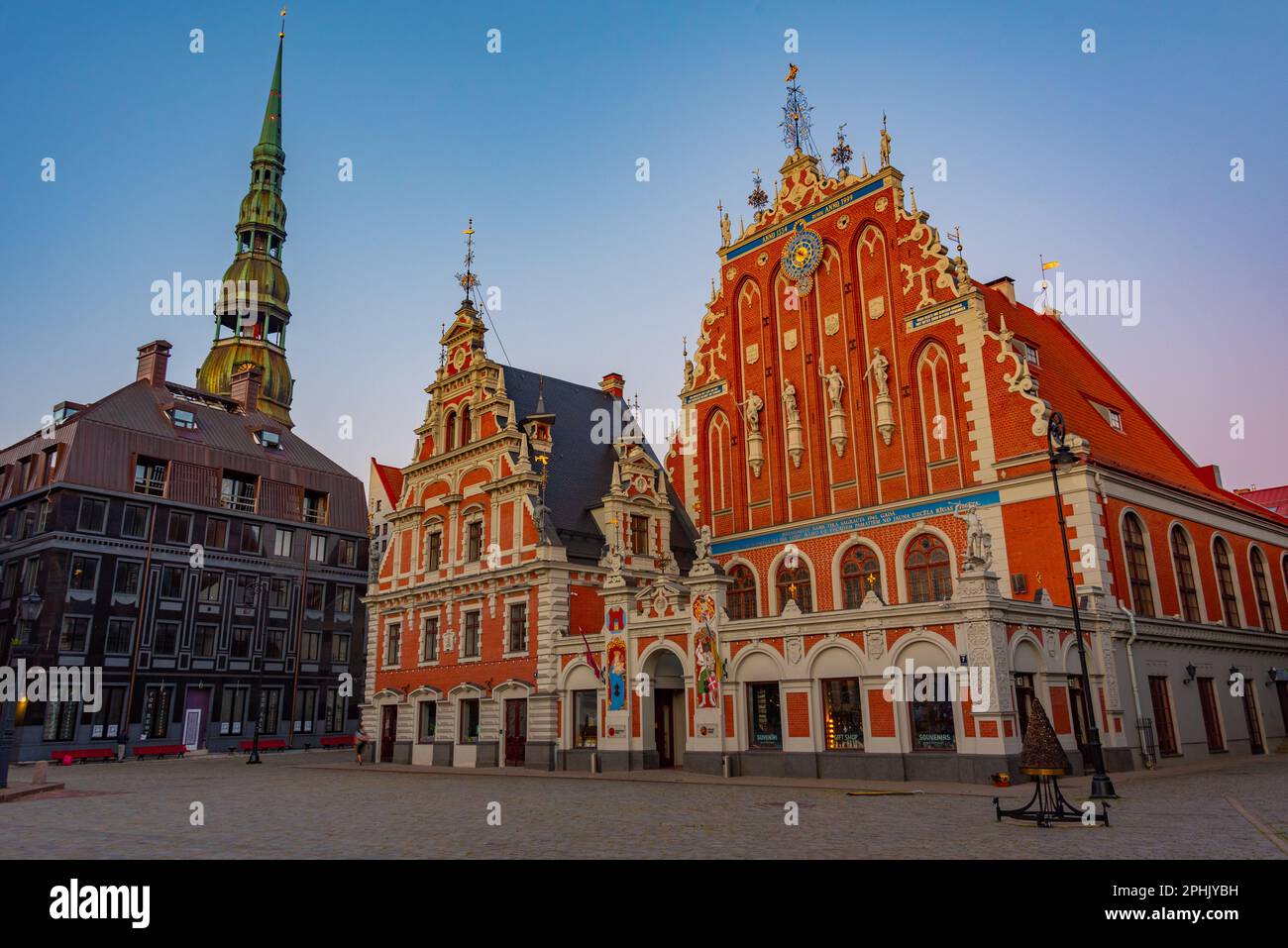 Coucher de soleil sur la place Ratslaukums avec église Saint-Pierre et Maison des Blackheads dans la vieille ville de Riga en Lettonie. Banque D'Images