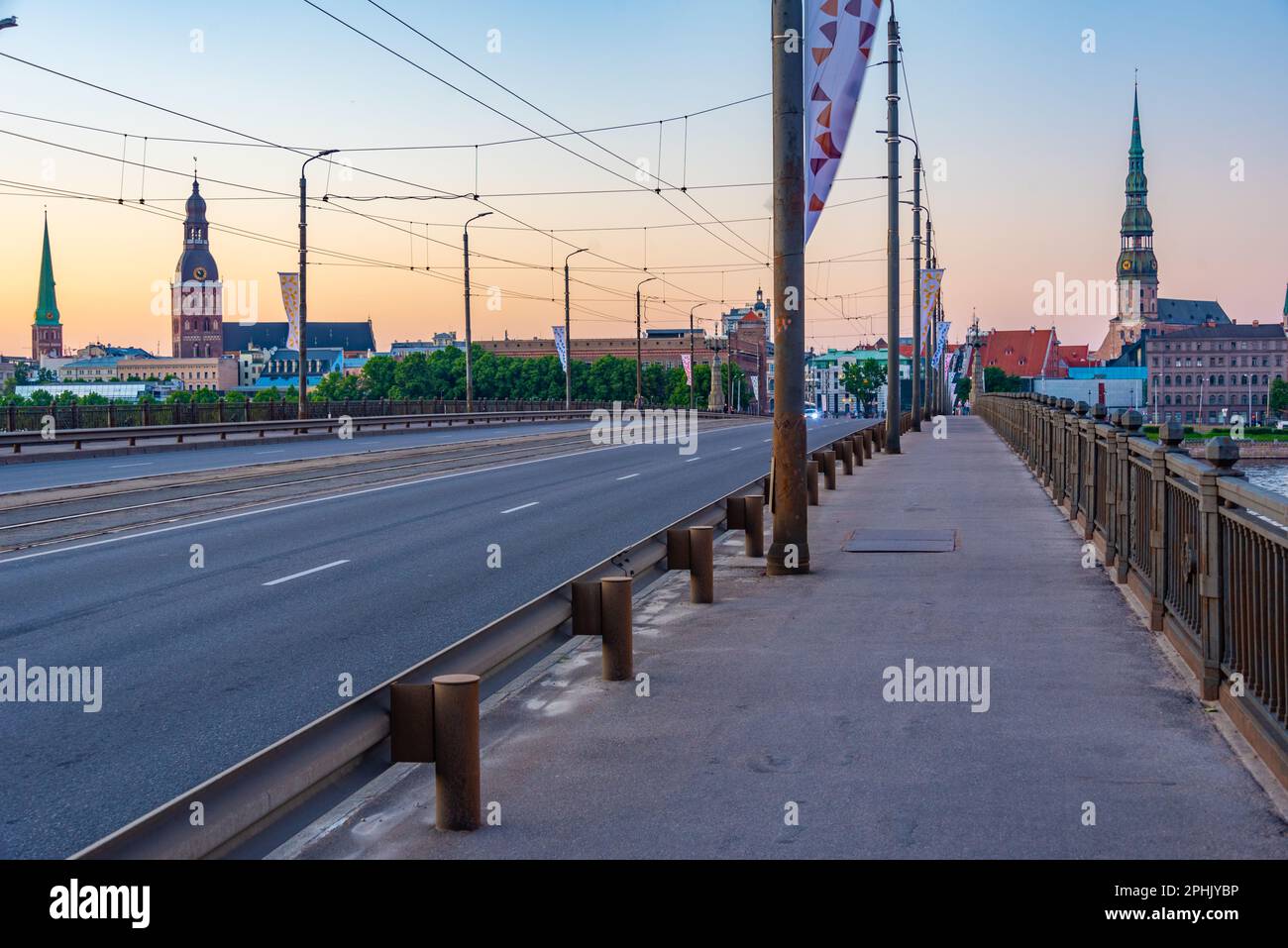 Coucher de soleil dans la vieille ville de riga, y compris l'église saint peters vue sur la rivière daugava, Lettonie. Banque D'Images