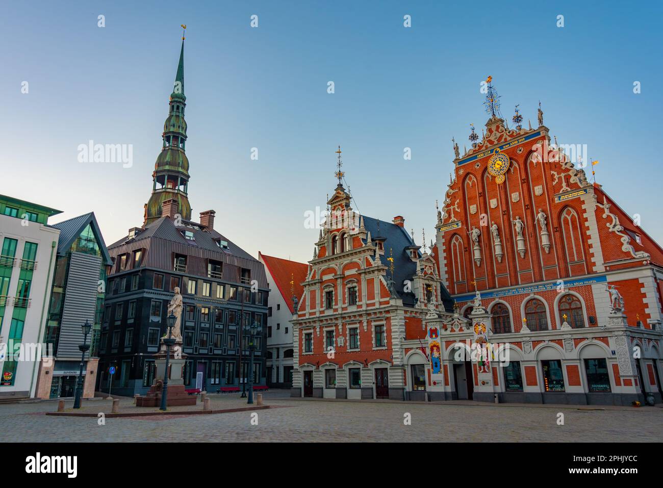 Lever du soleil sur la place Ratslaukums avec l'église Saint-Pierre et la Maison des Blackheads dans la vieille ville de Riga en Lettonie. Banque D'Images