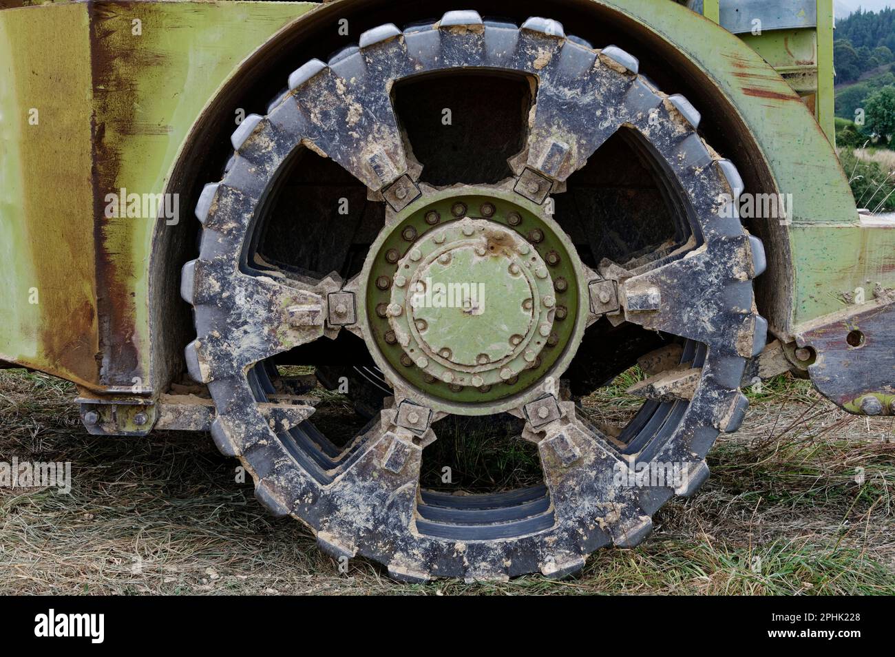 La boue adhère à la très grande roue métallique d'un gros morceau de machine en mouvement de terre. Banque D'Images