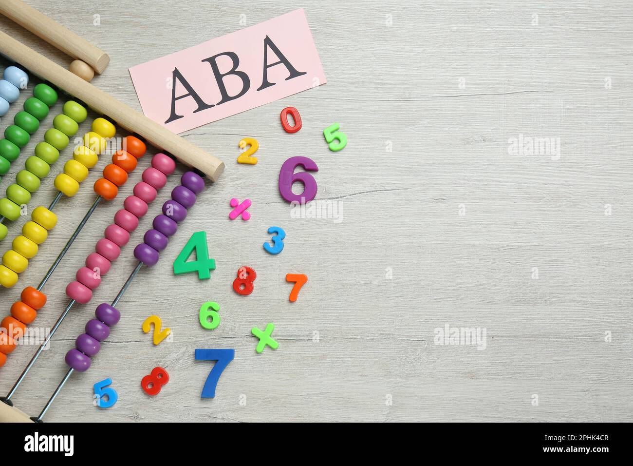 Feuille de papier avec abréviation ABA (Applied Behavior Analysis), abacus et nombres colorés sur table en bois blanc, plat. Espace pour le texte Banque D'Images