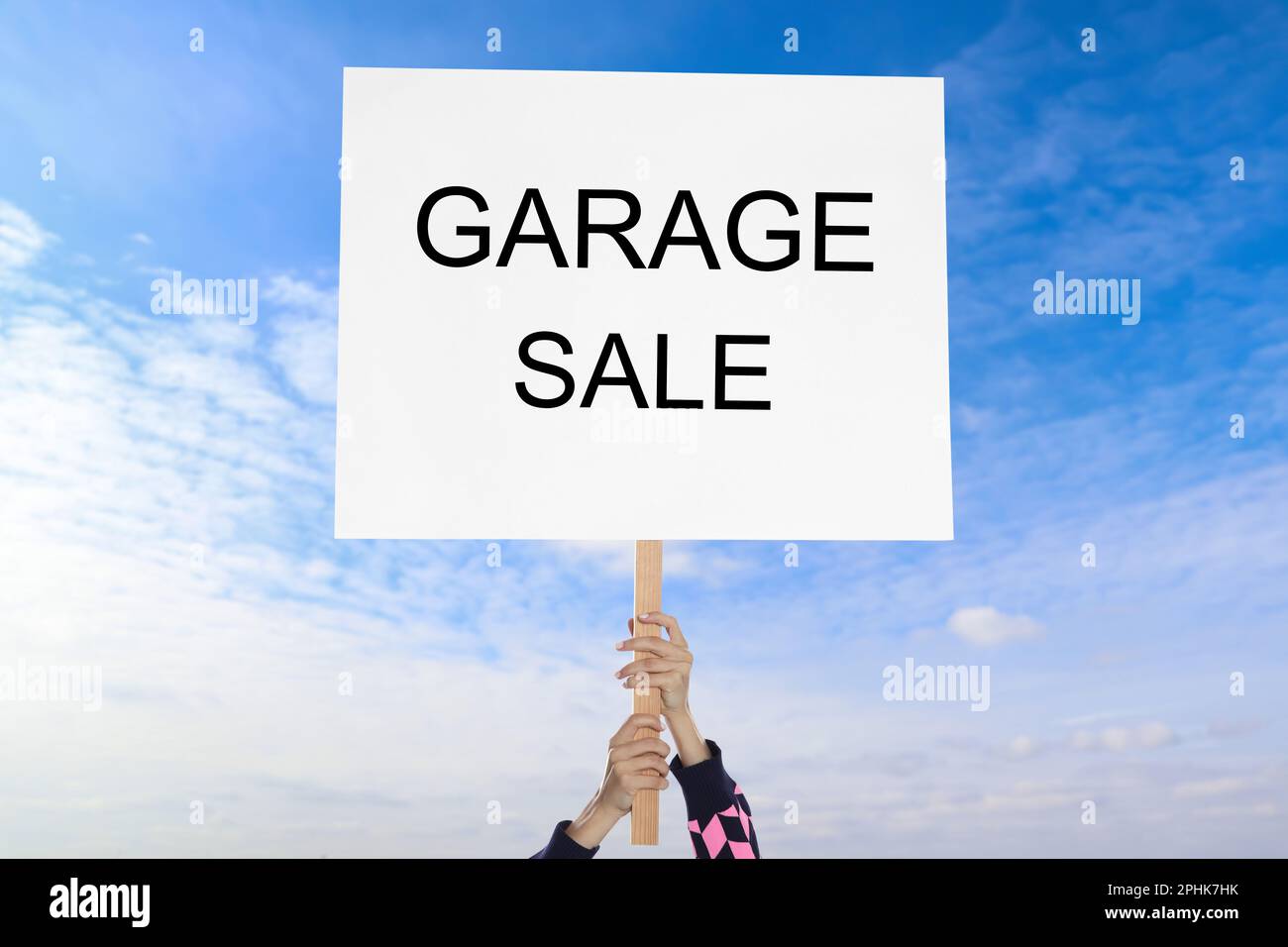 Femme tenant signe avec texte VENTE DE GARAGE contre ciel bleu Banque D'Images