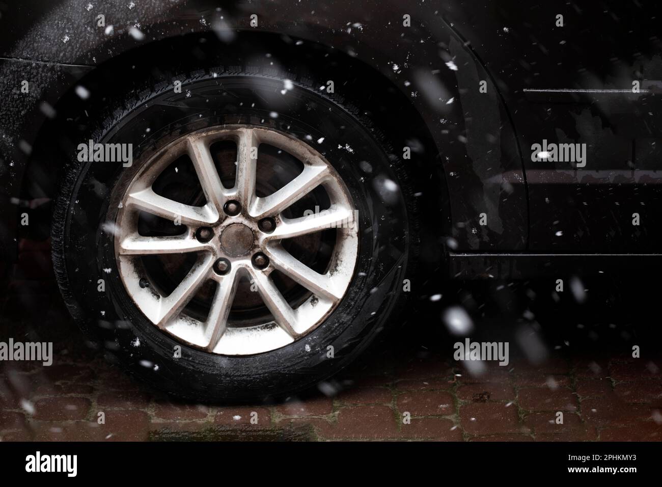 gros plan d'une roue de voiture dans des pneus d'hiver par mauvais temps avec de la neige. Phénomènes naturels anormaux Banque D'Images