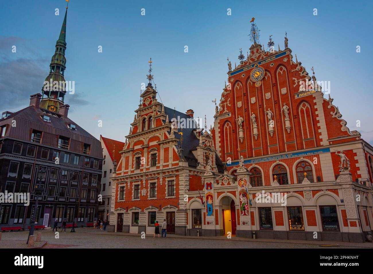 Coucher de soleil sur la place Ratslaukums avec église Saint-Pierre et Maison des Blackheads dans la vieille ville de Riga en Lettonie. Banque D'Images
