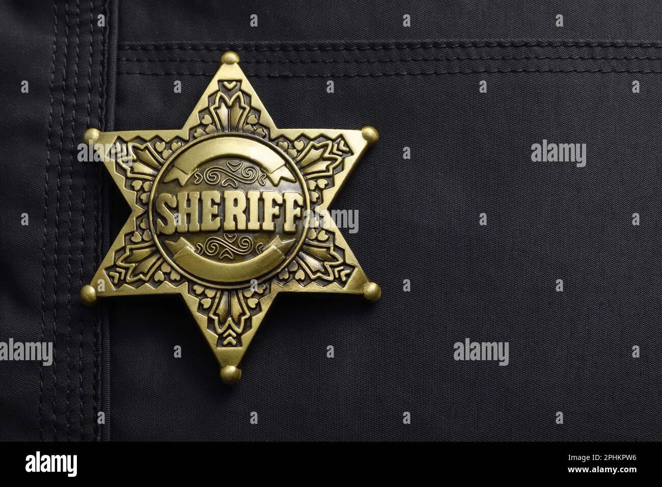 Un badge shérif en métal de couleur or en forme d'étoile à six pointes sur une veste noire Banque D'Images