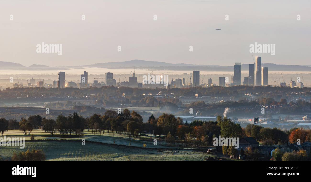 Tours lointaines de Manchester sur un hiver glacial matin avec un peu de brume dans l'air avec des collines, des arbres, des paysages et de la campagne en premier plan Banque D'Images