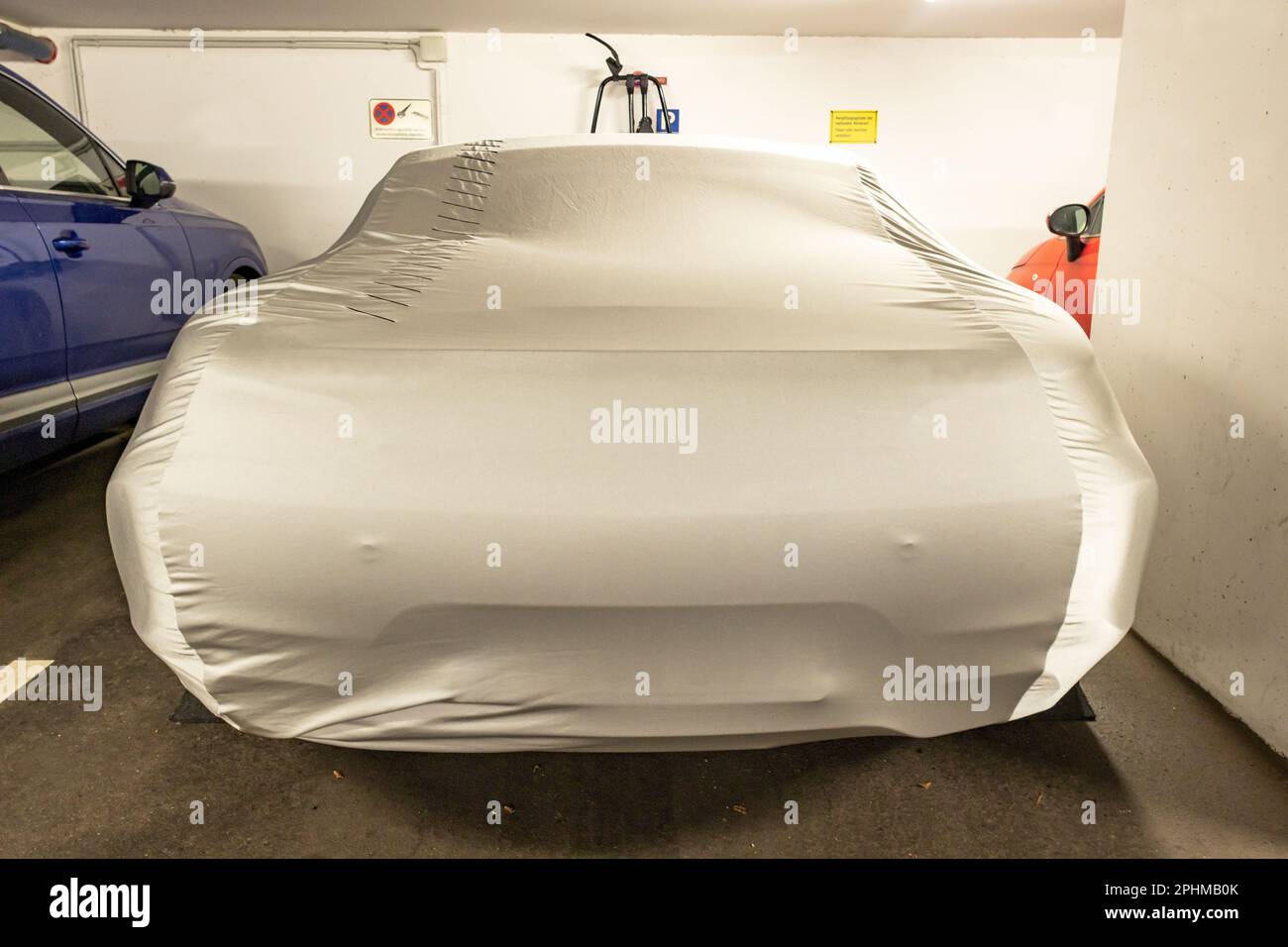 voiture de sport avec housse de protection dans le parking souterrain Banque D'Images