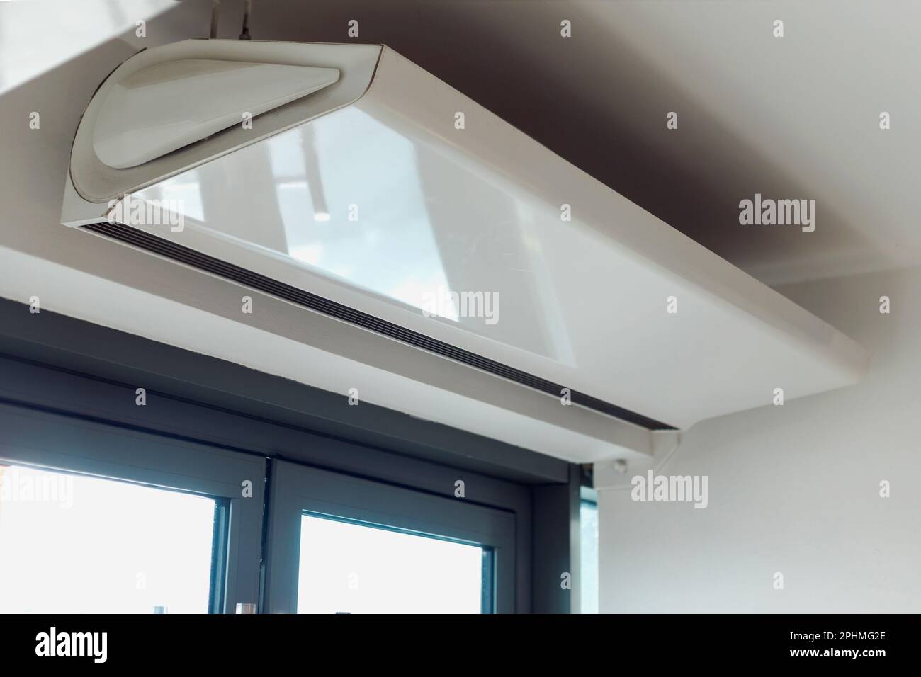 Rideau d'air électrique à écran thermique dans un bâtiment de bureau public. Ventilateur de chauffage automatique par le haut de la porte pour éviter la perte de chaleur Banque D'Images