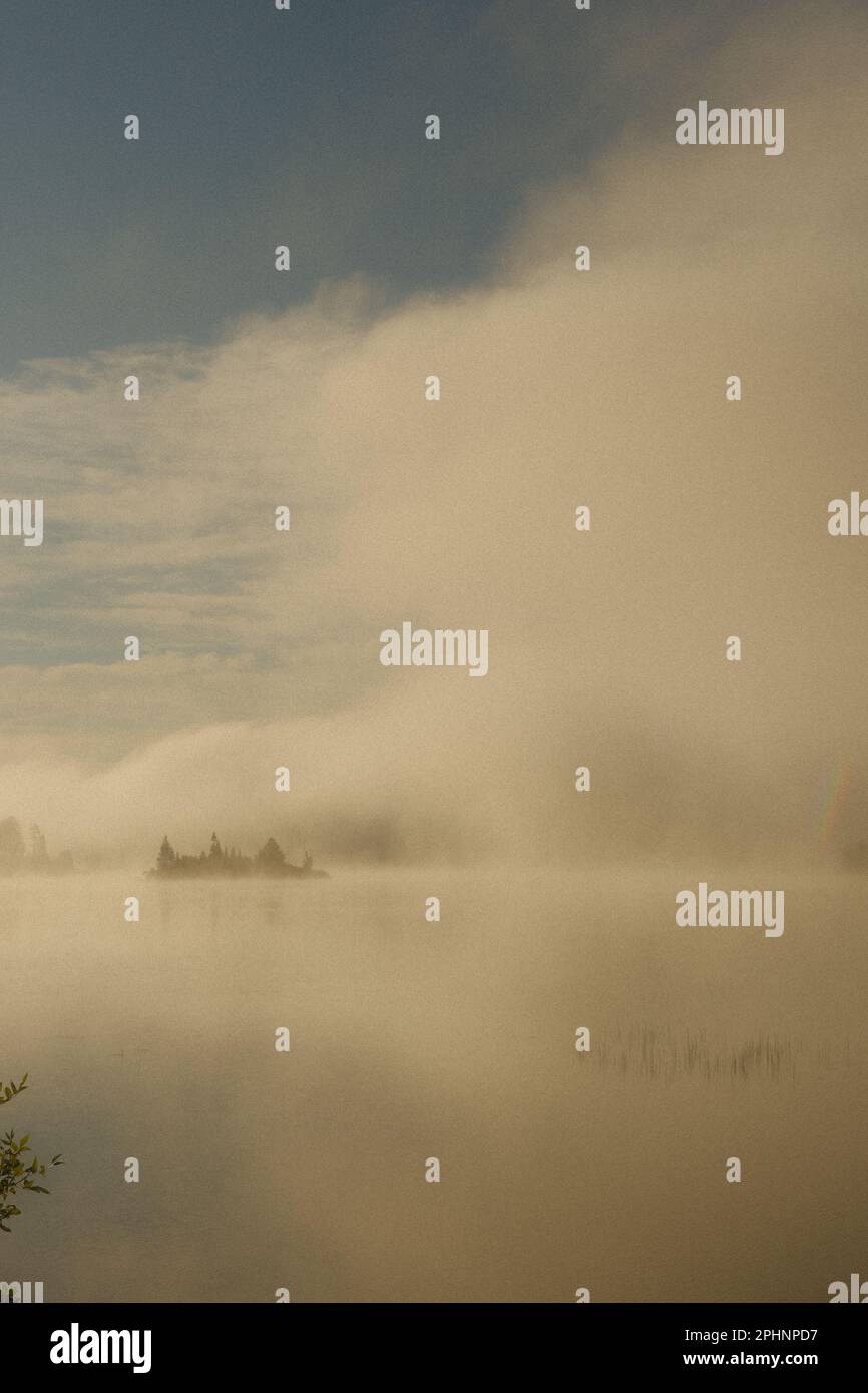 Brouillard qui survolez un lac et une île au lever du soleil Banque D'Images