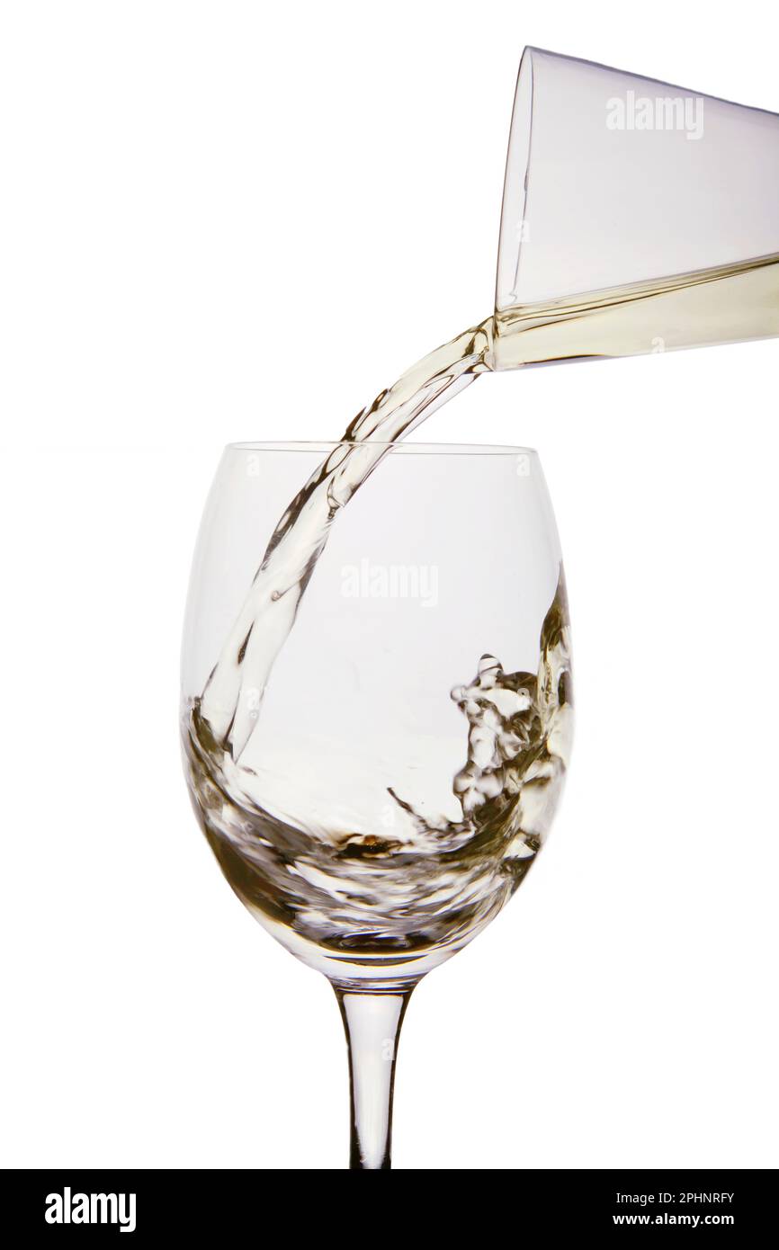 Verser le vin blanc d'une carafe dans un verre à vin Banque D'Images