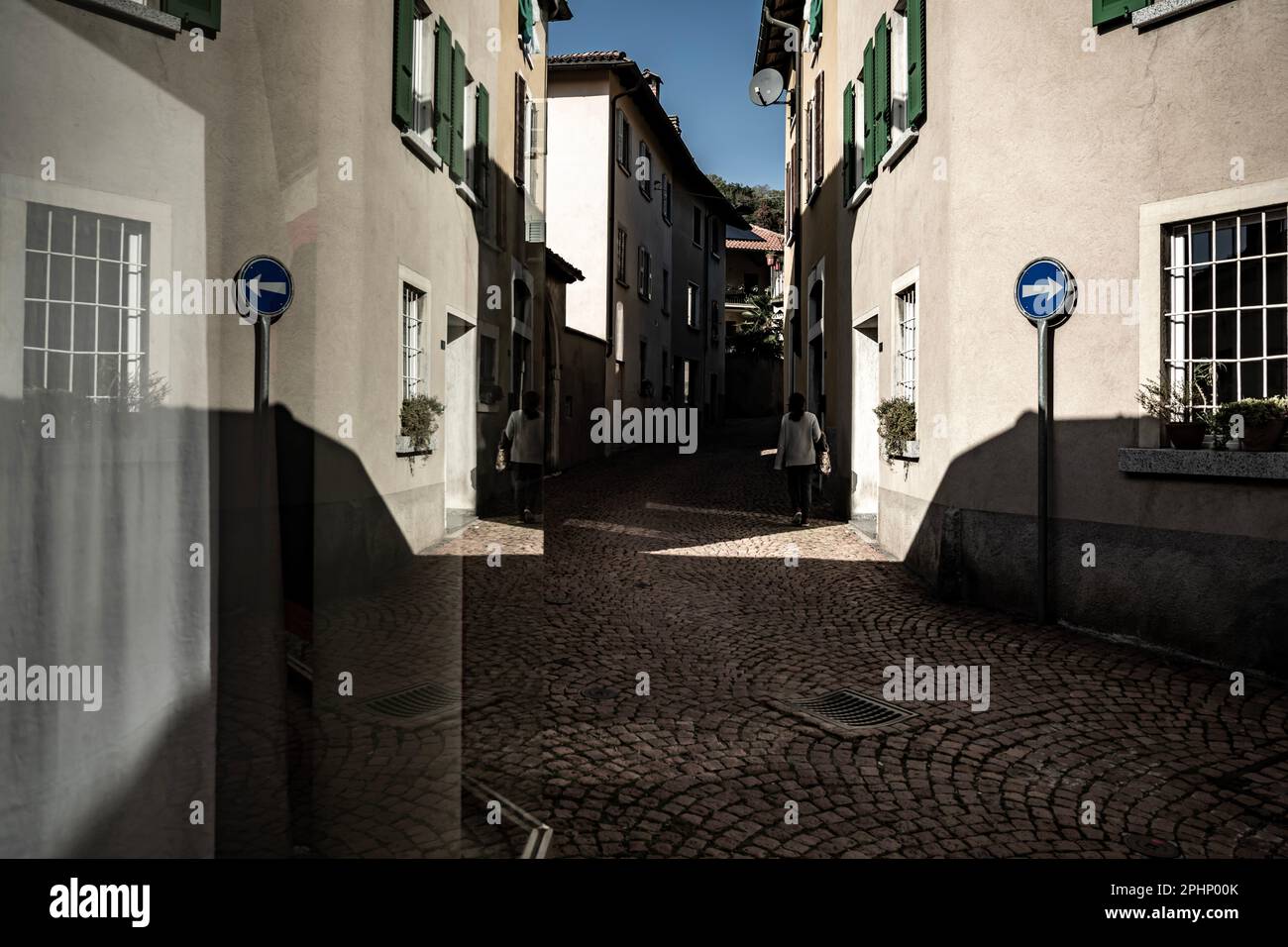 Route de la ville avec les vieilles maisons et la réflexion de fenêtre dans une journée ensoleillée à Arzo, Tessin, Suisse. Banque D'Images