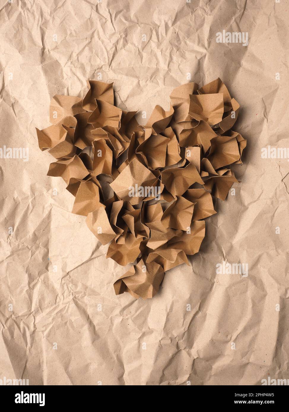 Forme de coeur fabriquée à partir de matériaux d'emballage en papier recyclé sur fond de papier recyclé écrasé Banque D'Images