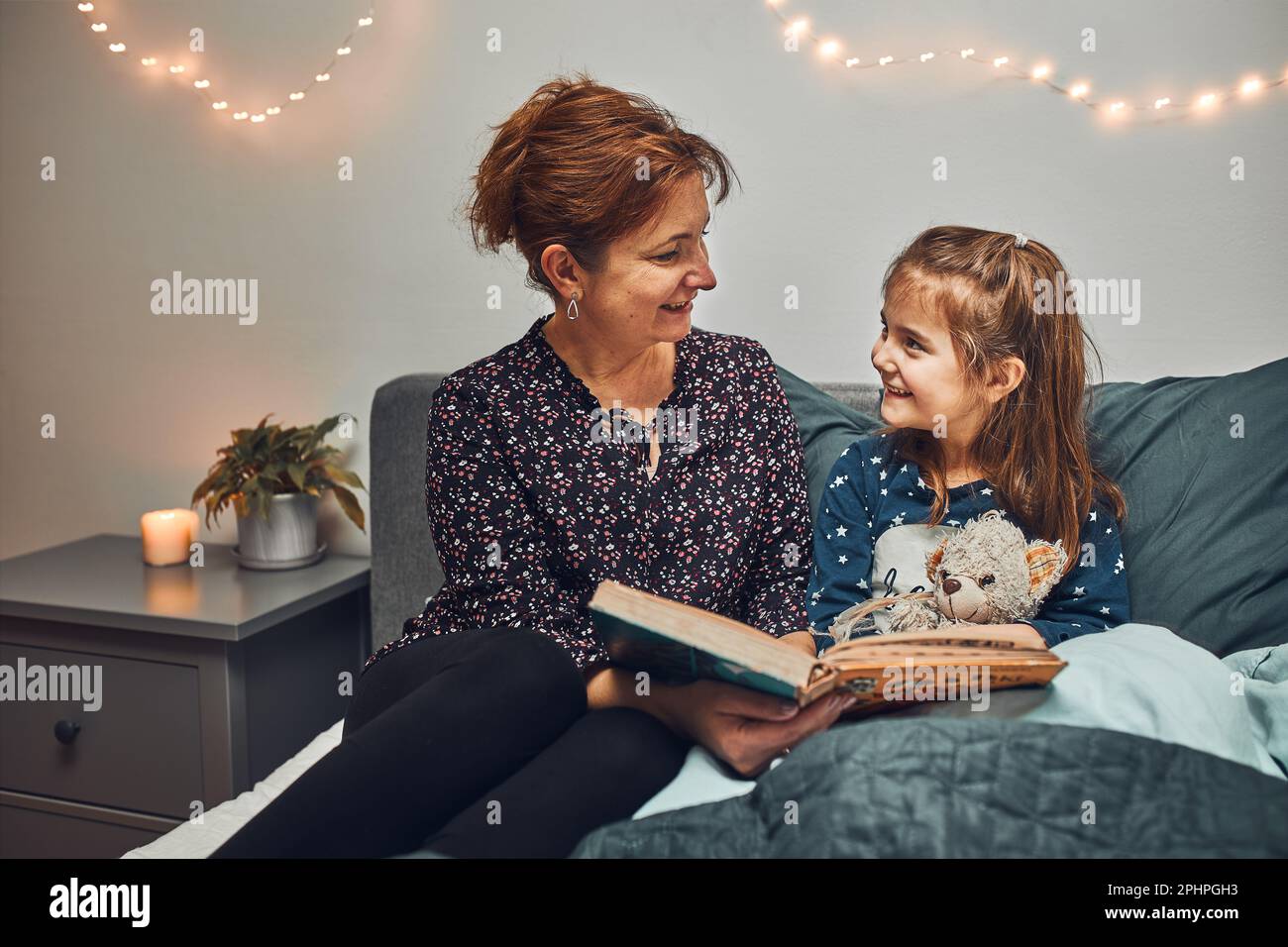 Mère lisant livre sa fille dans le lit avant d