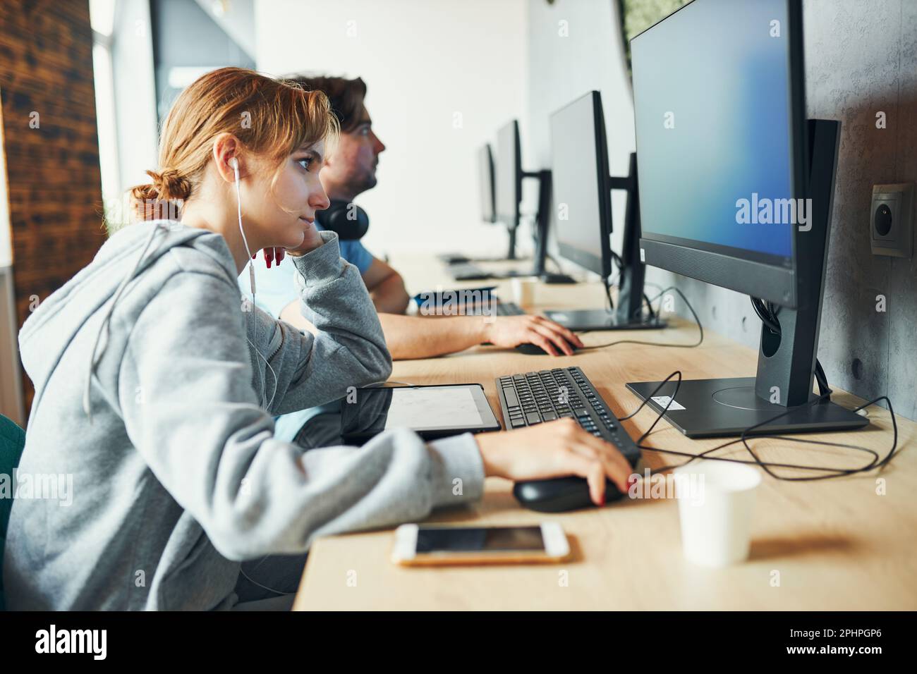 Les étudiants apprennent en classe informatique. Jeune homme se préparant pour le test sur ordinateur. Jeune fille écrivant un essai et prenant des notes à l'aide d'un ordinateur. Étudiant ciblé Banque D'Images