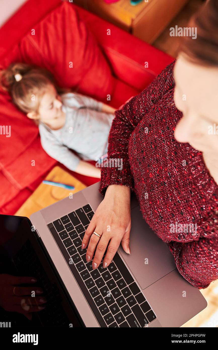 Femme mère qui travaille à distance pendant un webinaire de cours en ligne par vidéo chat et appel sur ordinateur portable depuis chez elle pendant la quarantaine COVID-19 pendant que h Banque D'Images