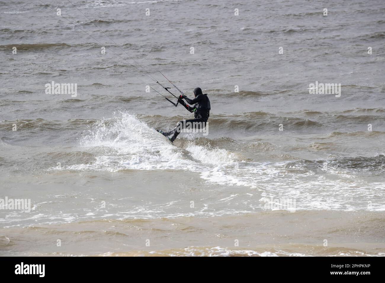 Kitesurfer en profitant des sensations fortes du surf sur les eaux agitées et agitées de la rive ouest de Llandudno dans des conditions venteuses Banque D'Images