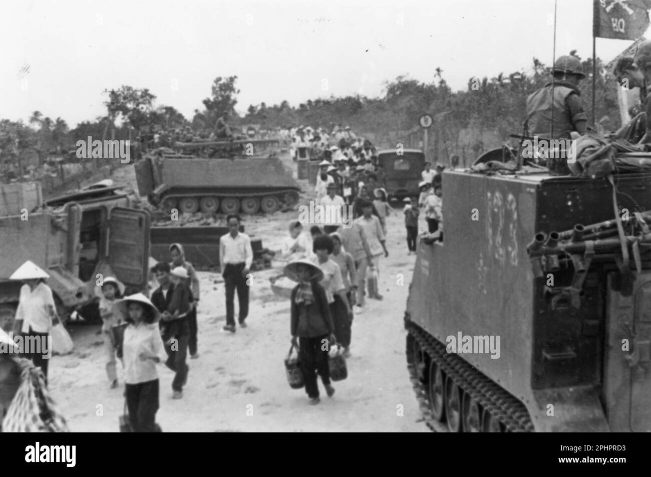 M-113 les transporteurs blindés de personnel restent près tandis que les réfugiés vietnamiens évacuent le village de My Tho, pendant l'offensive Tet. Vietnam du Sud, 1968. Photo par US signal corps) Banque D'Images