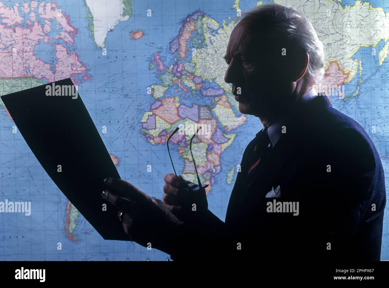 1990 UN HOMME DE BUREAU DÉTOURÉ HISTORIQUE LISANT LE DOCUMENT SUR LA CARTE DU MONDE (©RAND MCNALLY 1990) Banque D'Images