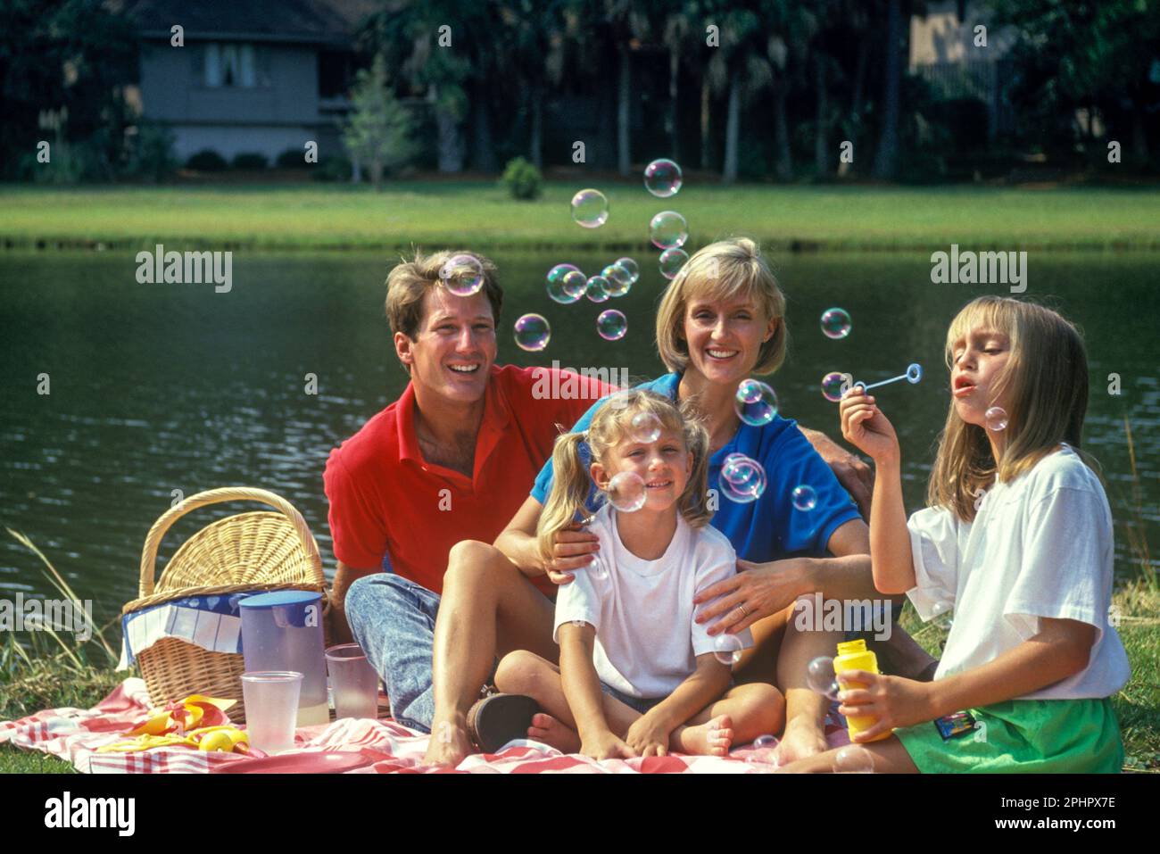 1990 FAMILLE HISTORIQUE ASSIS À L'EXTÉRIEUR SUR UN PIQUE-NIQUE PRÈS DU LAC DANS LA BANLIEUE SUD-AMÉRICAINE Banque D'Images