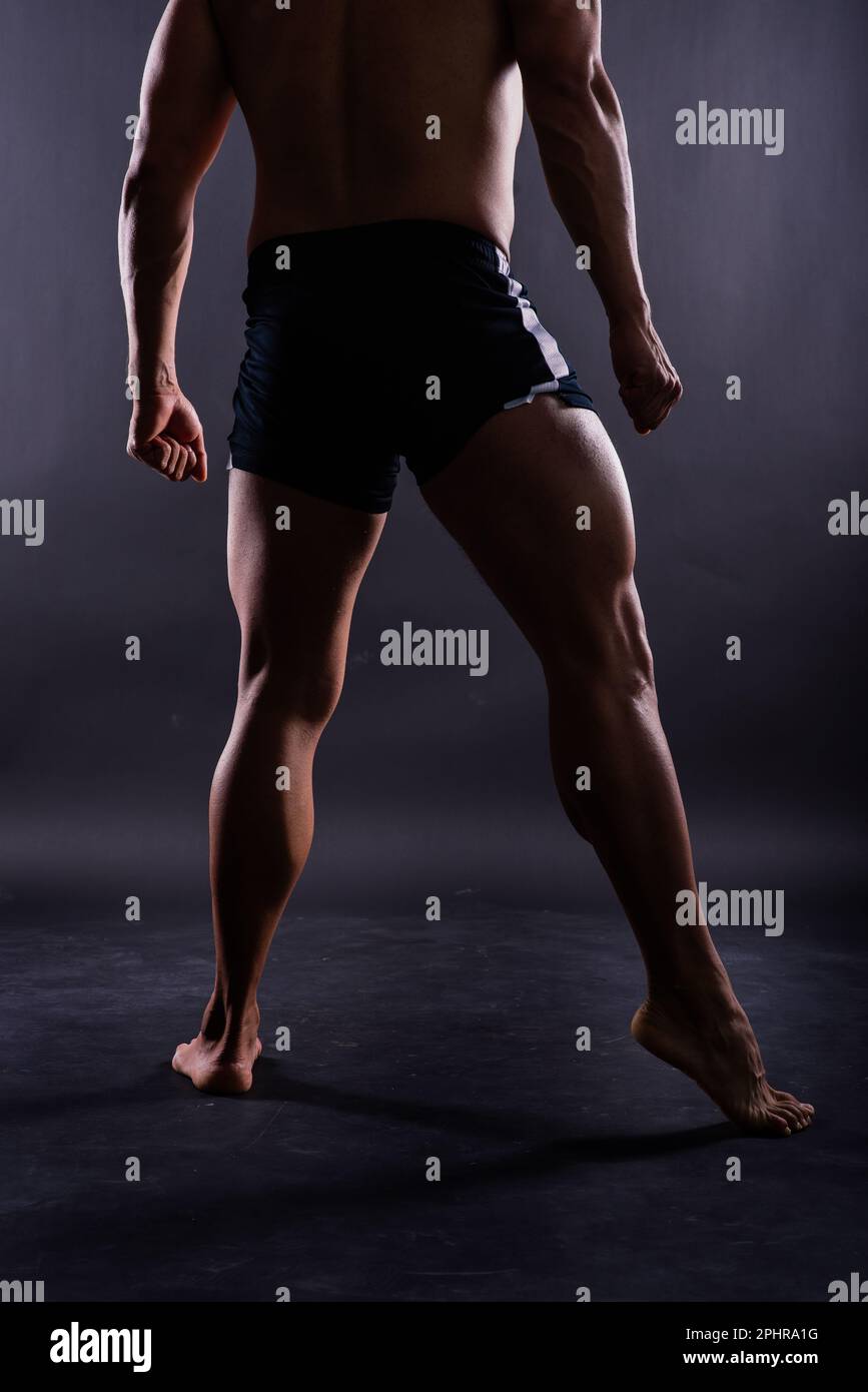 Musclés jambes mâles gros plan studio tourné sur fond sombre Banque D'Images
