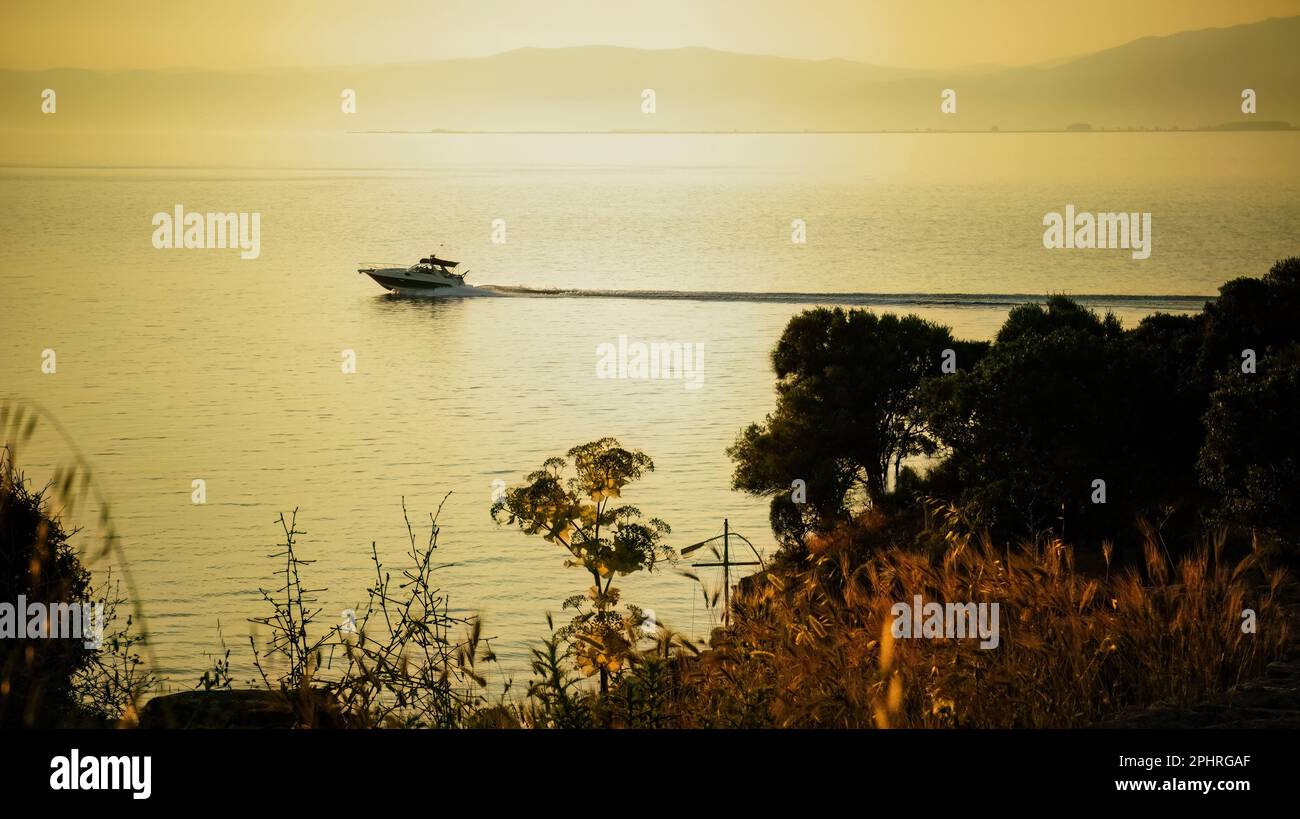 Magnifique coucher de soleil sombre et nuageux dans la mer avec silhouette d'arbre et de bateau Banque D'Images