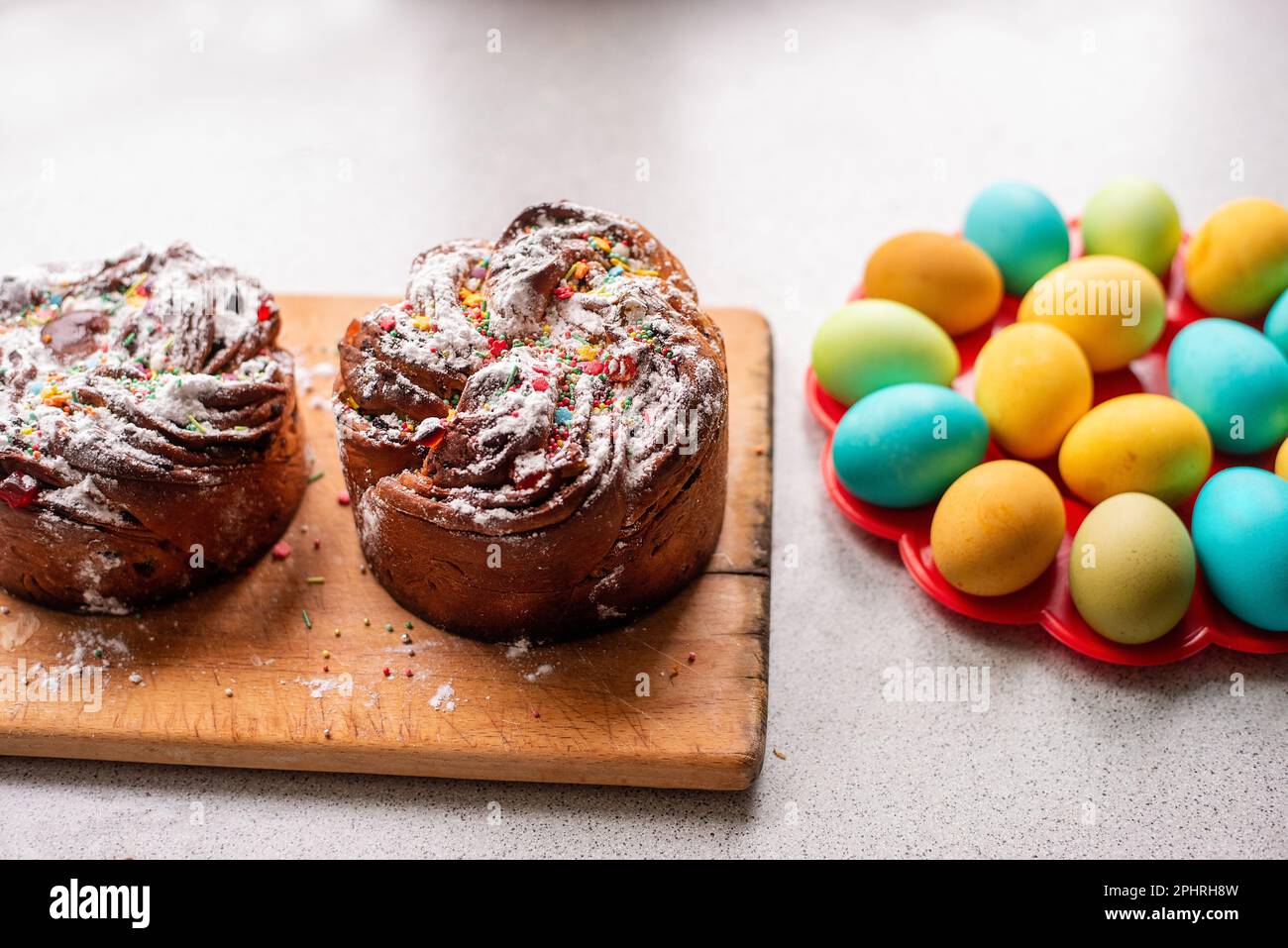 Kraffin de Pâques sur fond clair avec des œufs colorés et lumineux. Gâteau aux fruits confits, raisins secs, chocolat, noix, garniture au sucre en poudre, edibl Banque D'Images