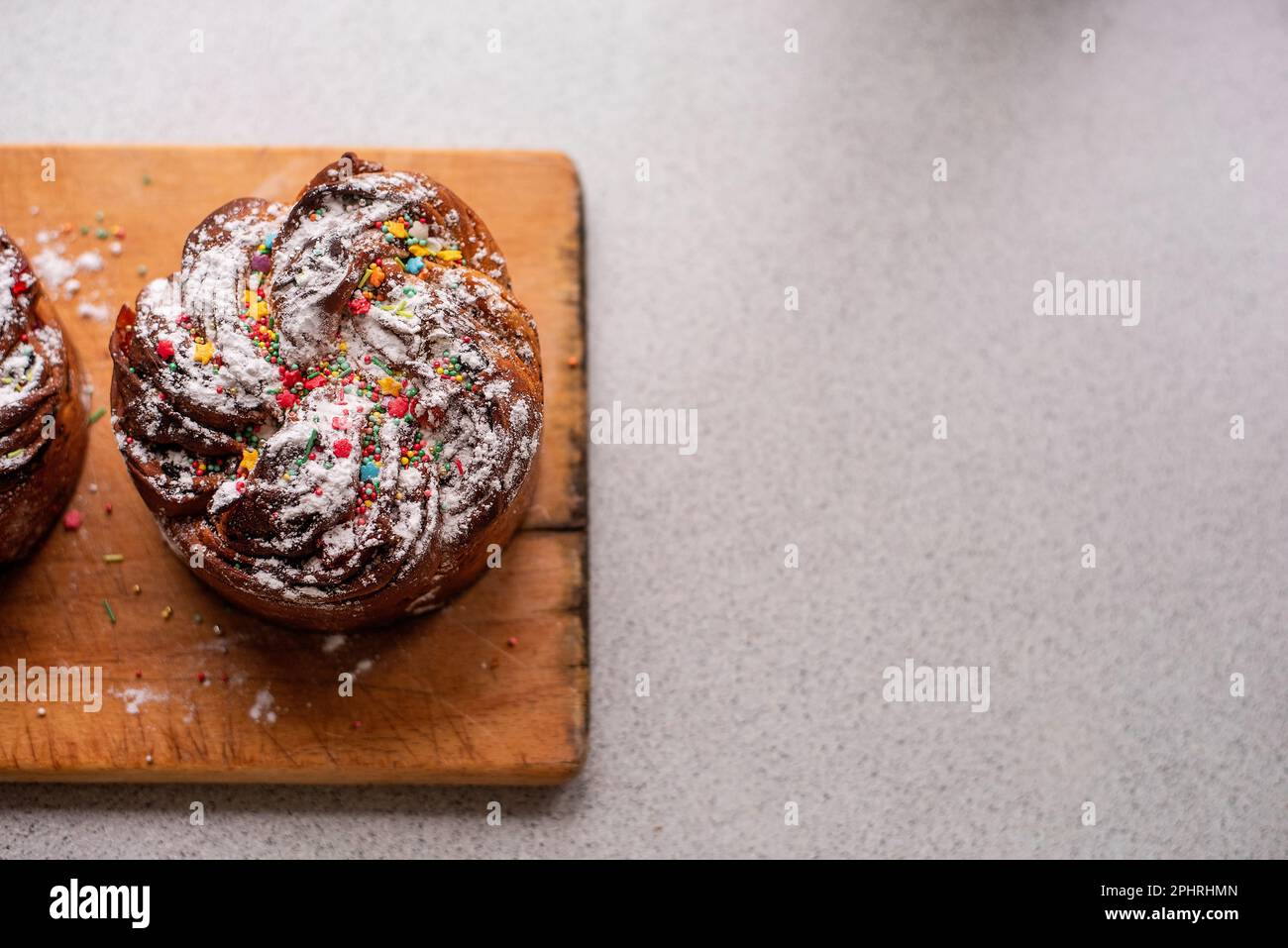 Kraffin de Pâques sur fond de bois clair. Gâteau aux fruits confits, raisins secs, chocolat, noix, garniture au sucre en poudre, décorations comestibles. Rustique Banque D'Images