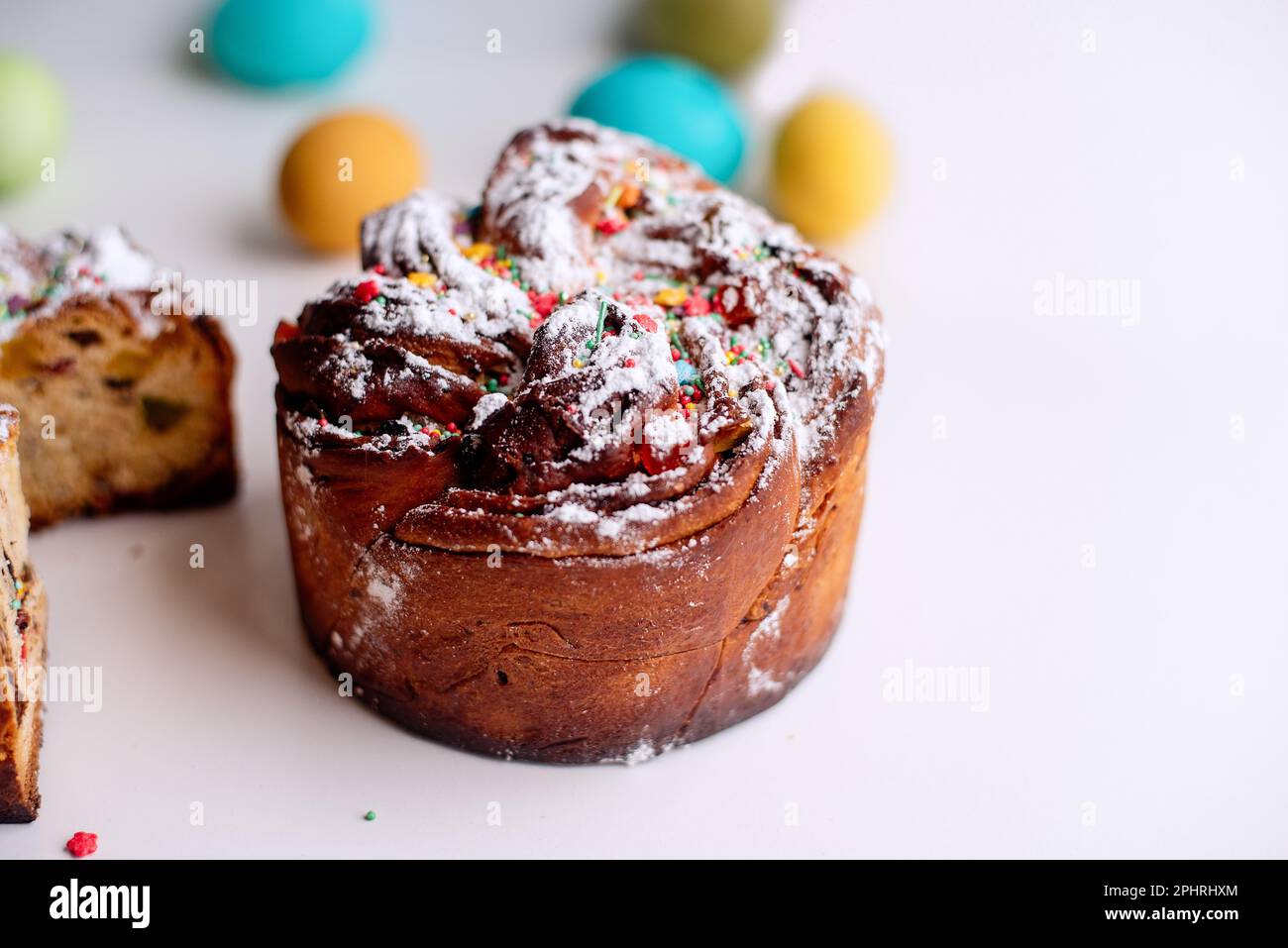 Kraffin de Pâques sur fond clair avec des œufs colorés et lumineux. Gâteau aux fruits confits, raisins secs, chocolat, noix, garniture au sucre en poudre, edibl Banque D'Images