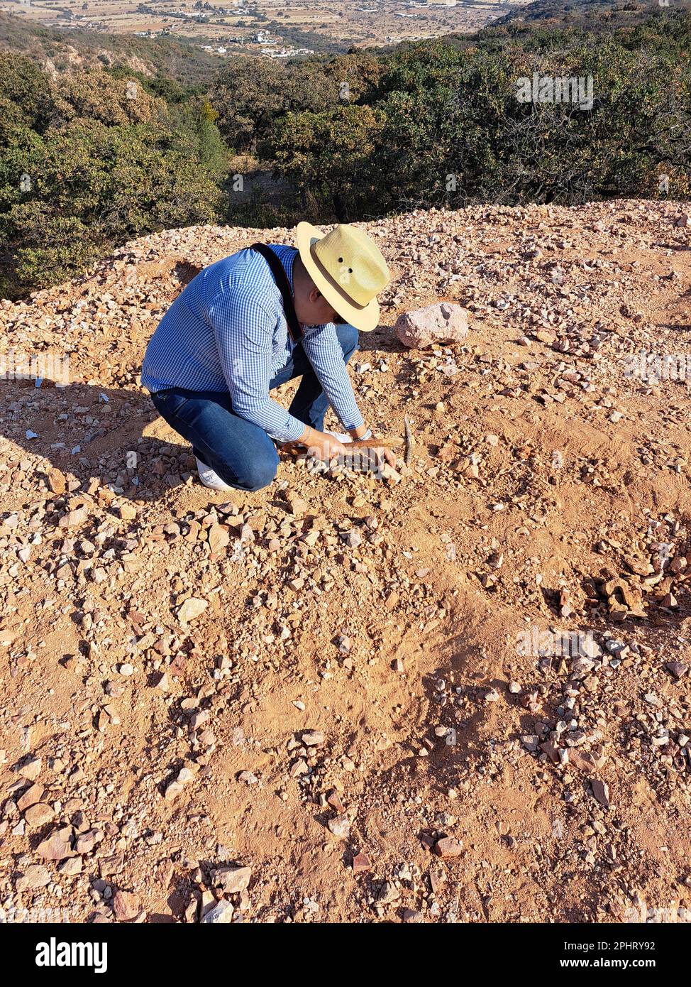 L'homme latin avec chapeau et marteau à piquer du mineur travaille comme géologue, étudie la composition et la structure du sol minéral de la montagne Banque D'Images