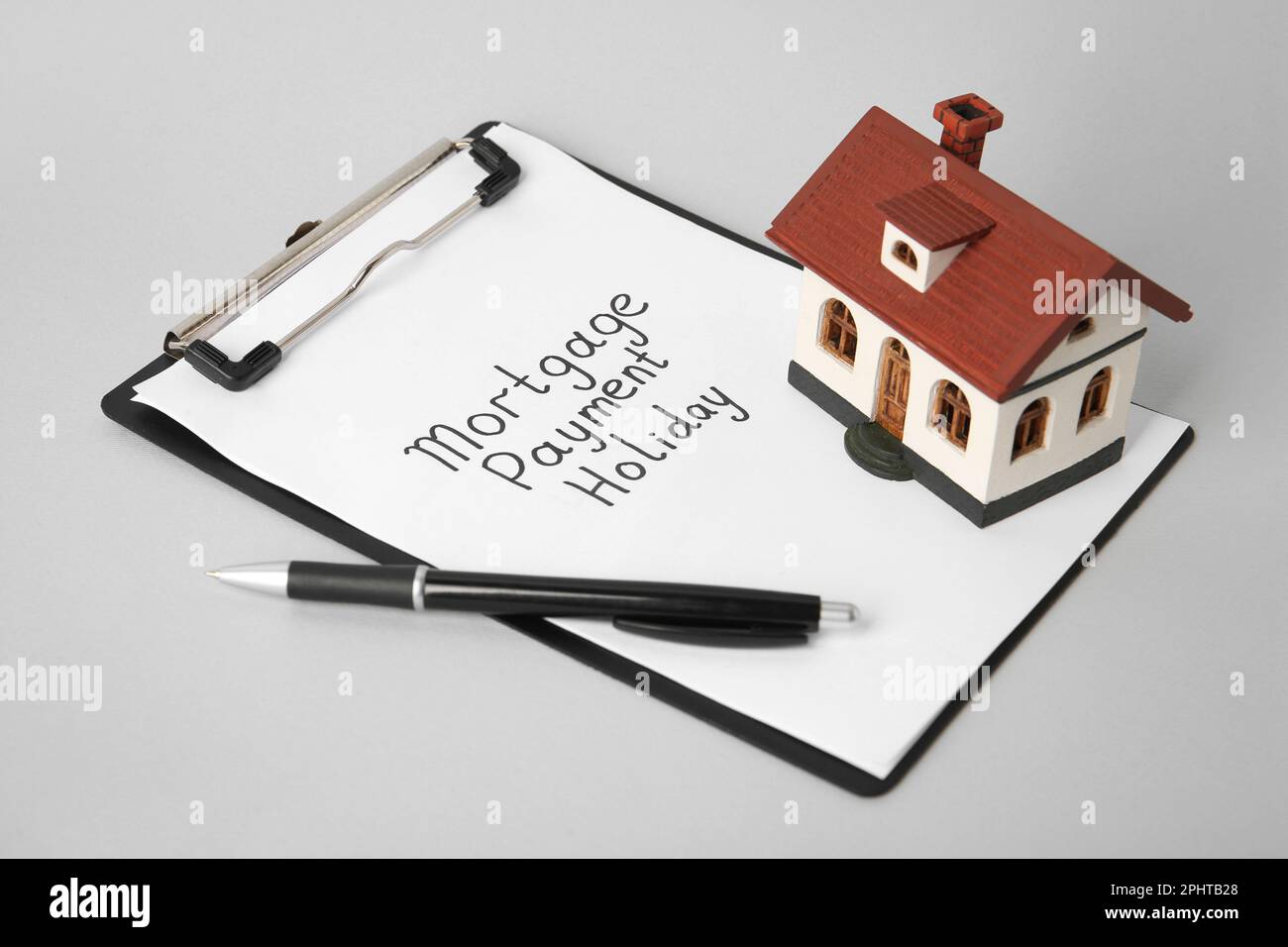 Modèle de maison, presse-papiers avec texte hypothèque paiement vacances et stylo sur table gris clair Banque D'Images