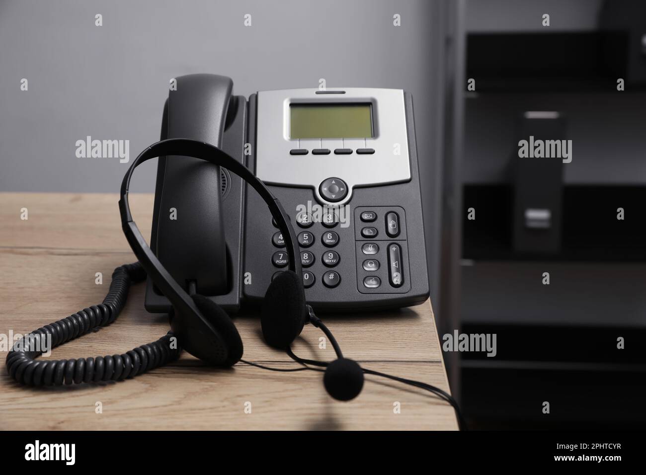 Téléphone fixe et casque sur un bureau en bois à l'intérieur. Service d'assistance téléphonique Banque D'Images