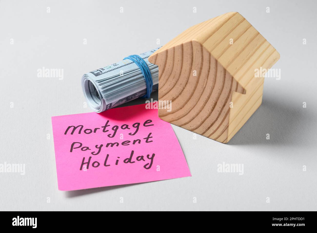 Papier note avec des mots paiement hypothécaire vacances, argent et modèle de maison sur fond gris clair, gros plan Banque D'Images