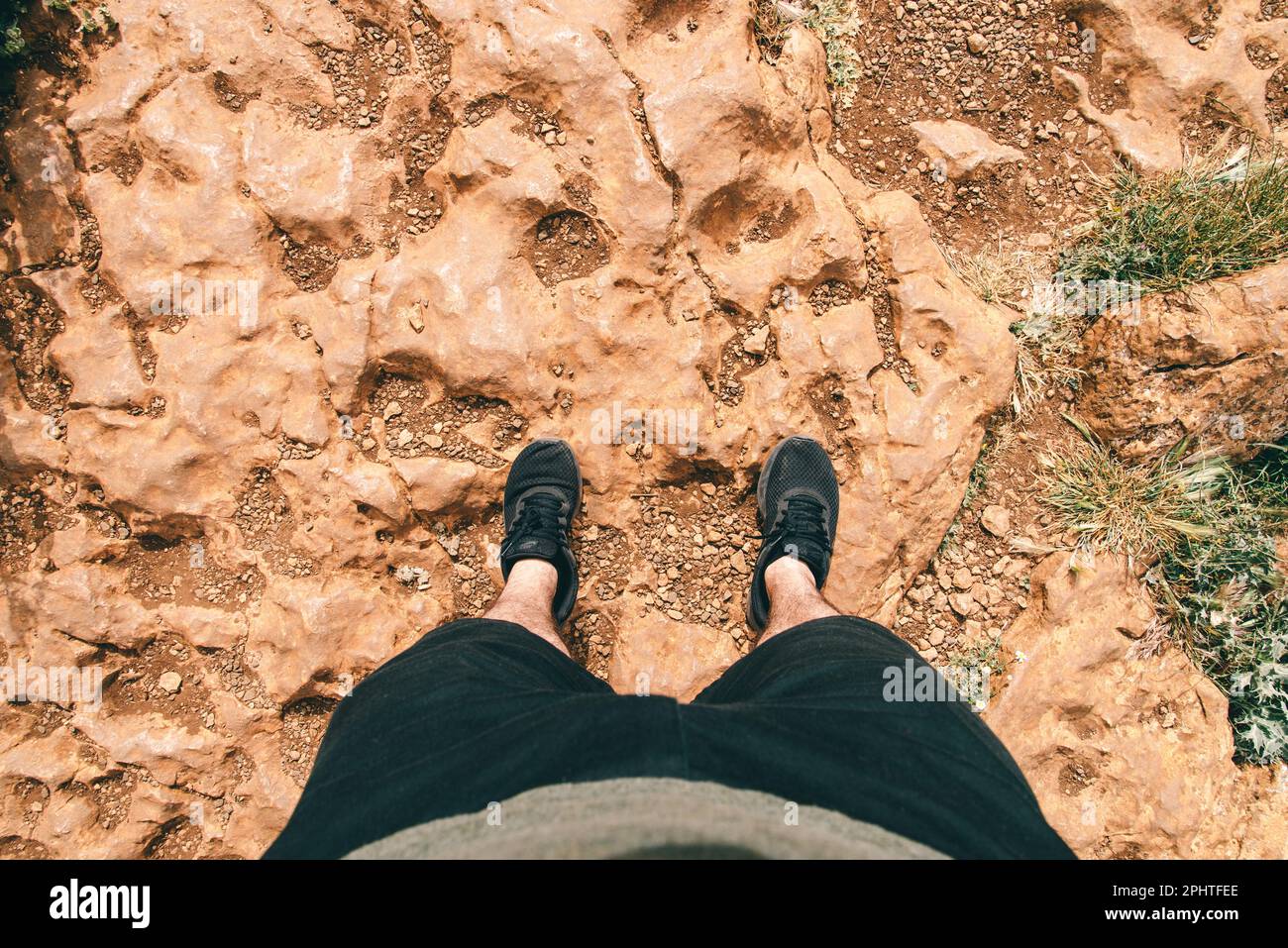 Homme POV jambes et pieds debout sur le sol de roche Banque D'Images