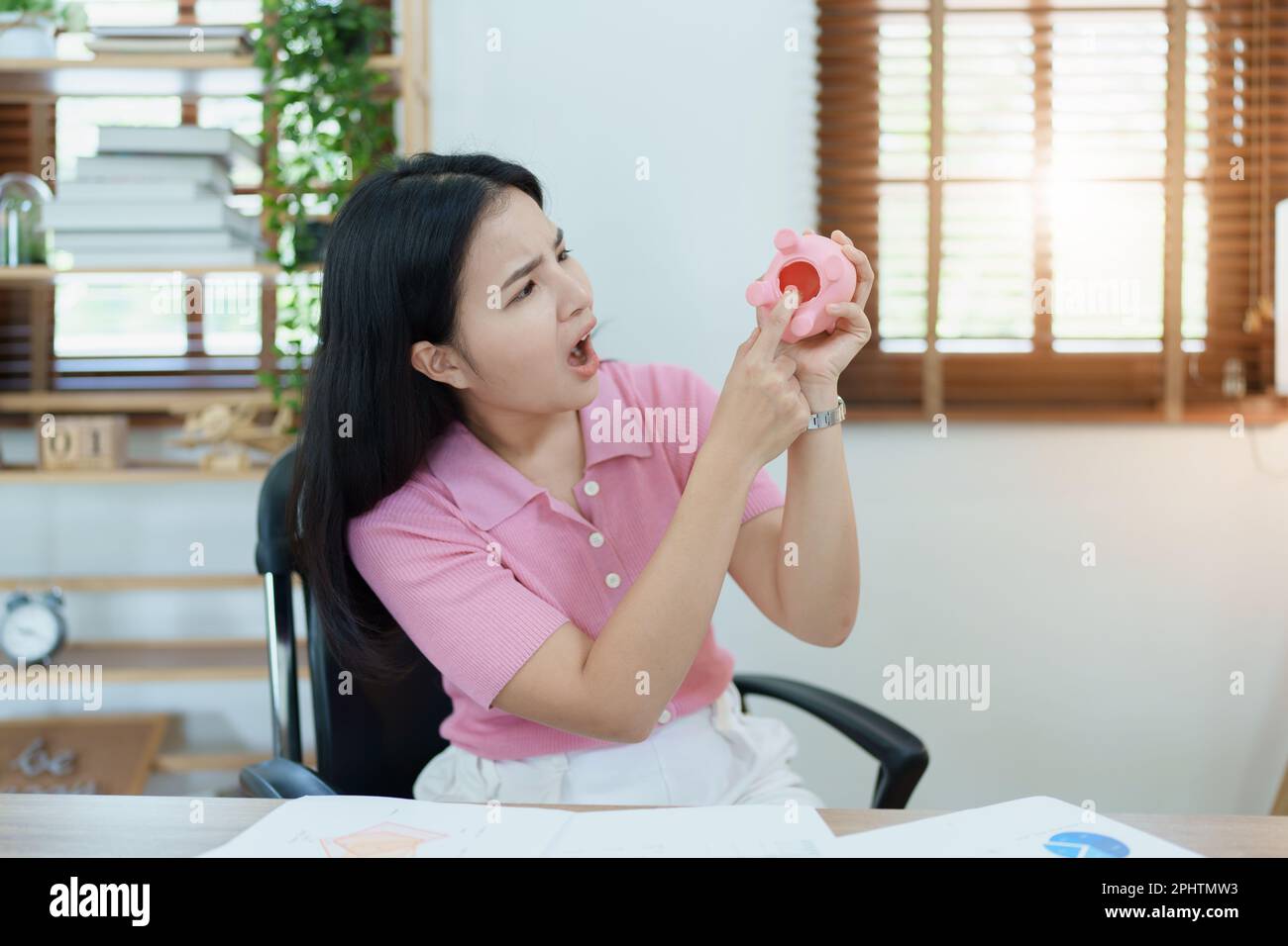 Portrait d'une femme d'affaires asiatique montrant une expression sérieuse et anxieuse dans une entreprise de PME , mais pas d'argent dans la banque de porc rose Banque D'Images