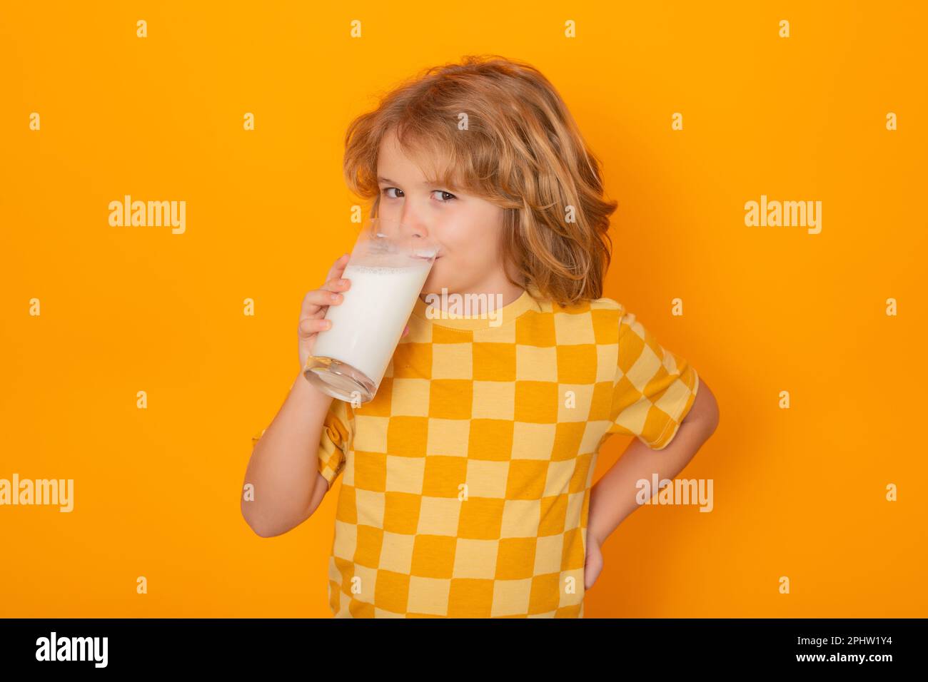 Enfant avec un verre de lait sur fond jaune studio. Enfant avec moustache en lait. Portrait amusant d'un enfant mignon avec moustache en lait et visage amusant. Dri. Enfant Banque D'Images