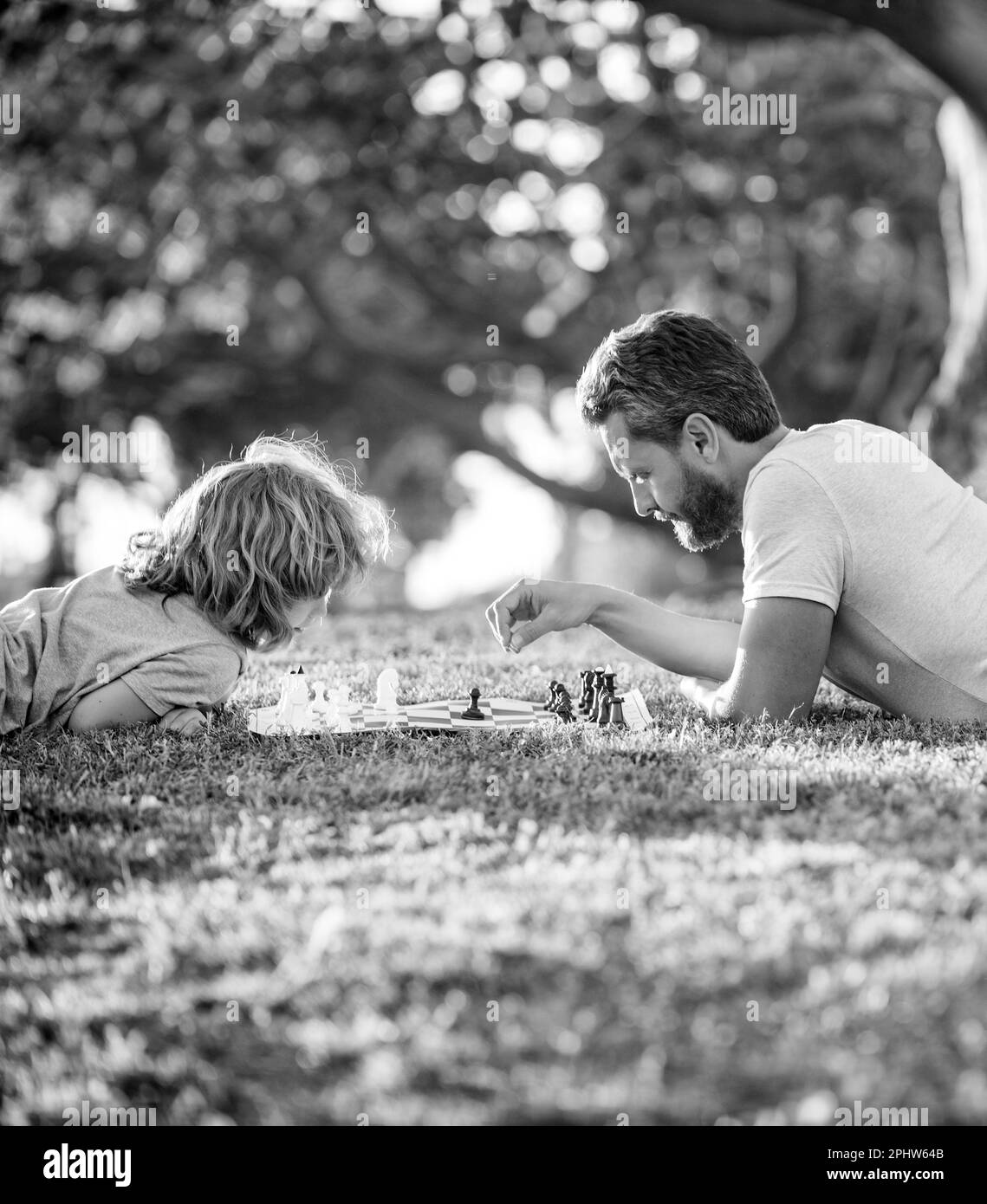 père et fils jouant aux échecs sur l'herbe verte. fête des pères. famille heureuse. famille parenthood Banque D'Images