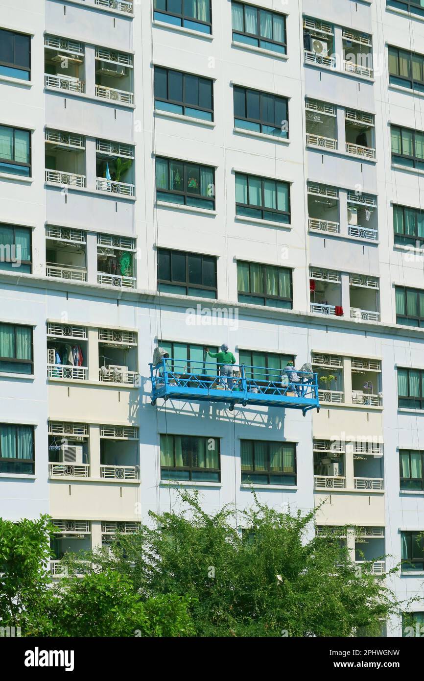Deux des ouvriers d'accès à la corde peignant la façade d'un bâtiment moderne de haut niveau Banque D'Images